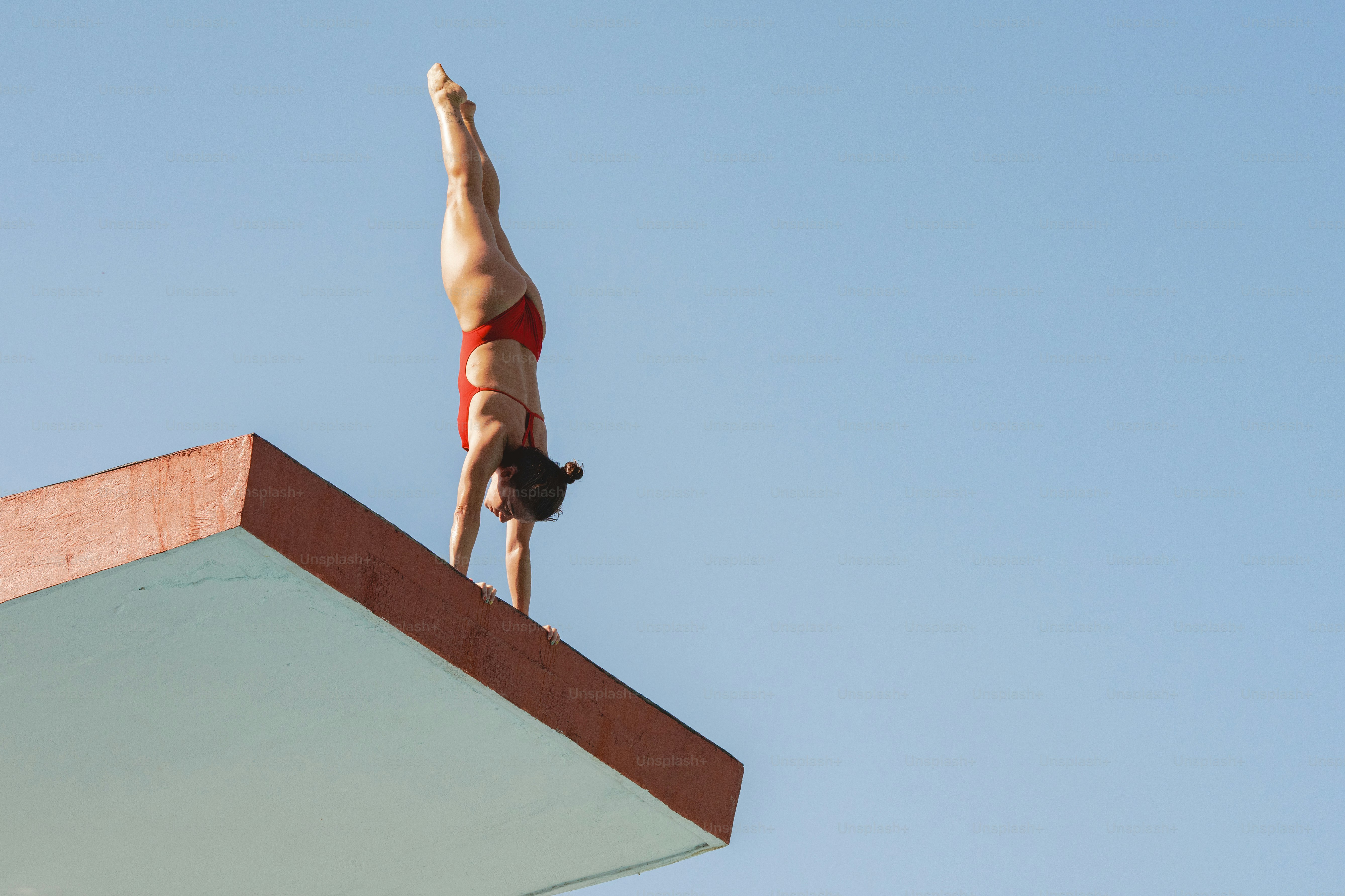 A man in a red swimsuit diving off of a diving platform