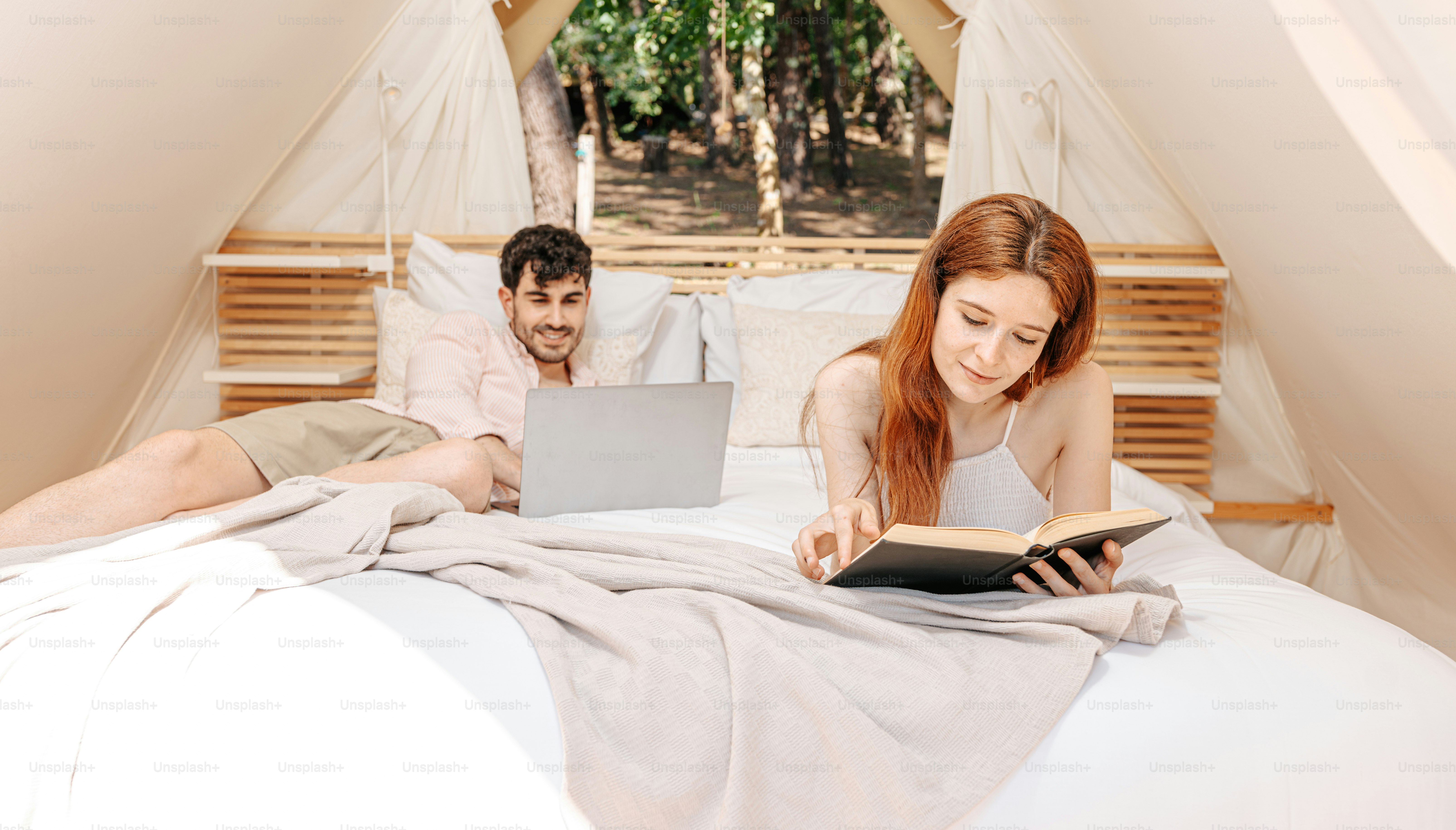 A man and a woman laying in bed with a laptop