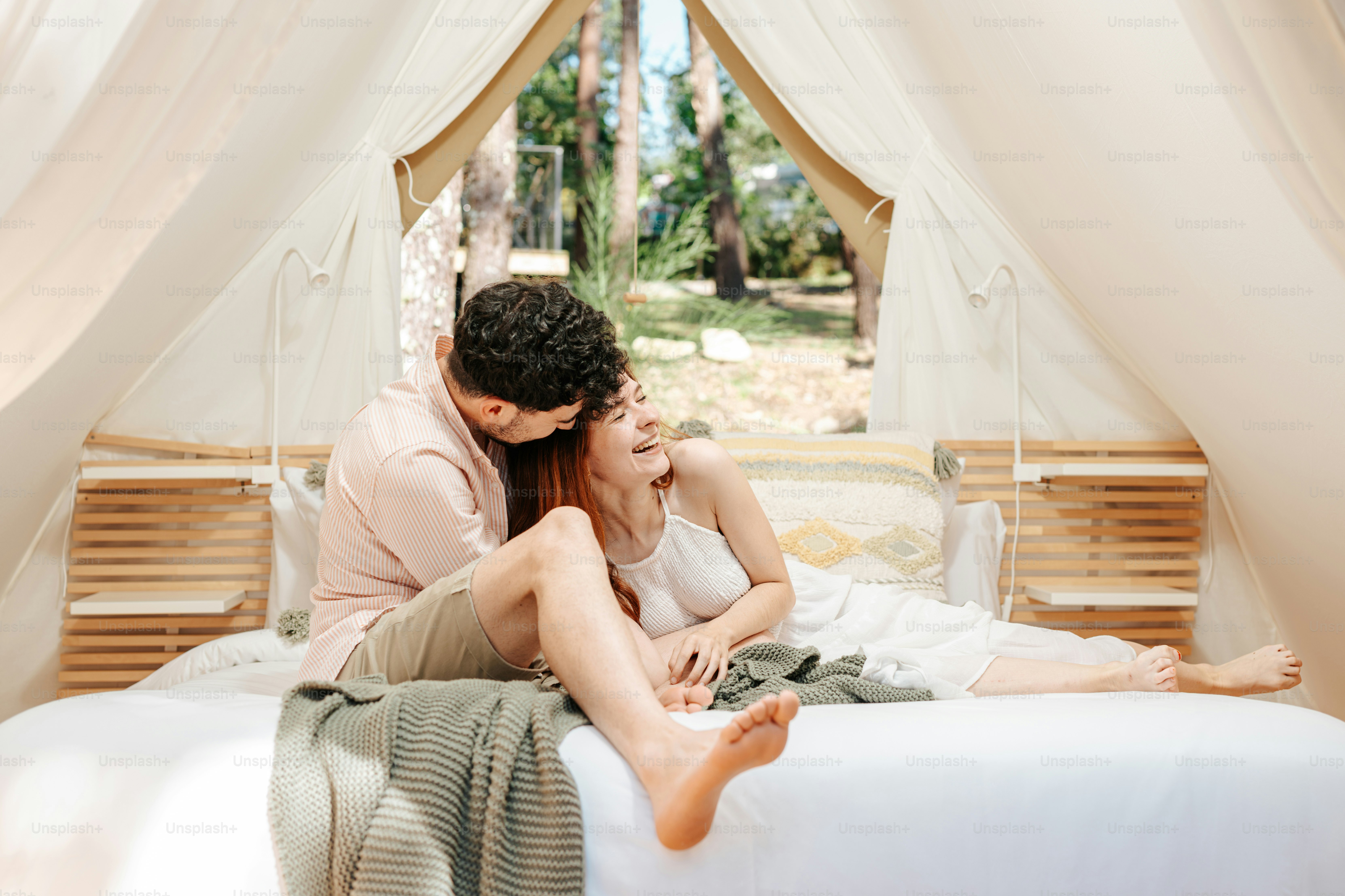 A man and woman sitting on a bed in a tent