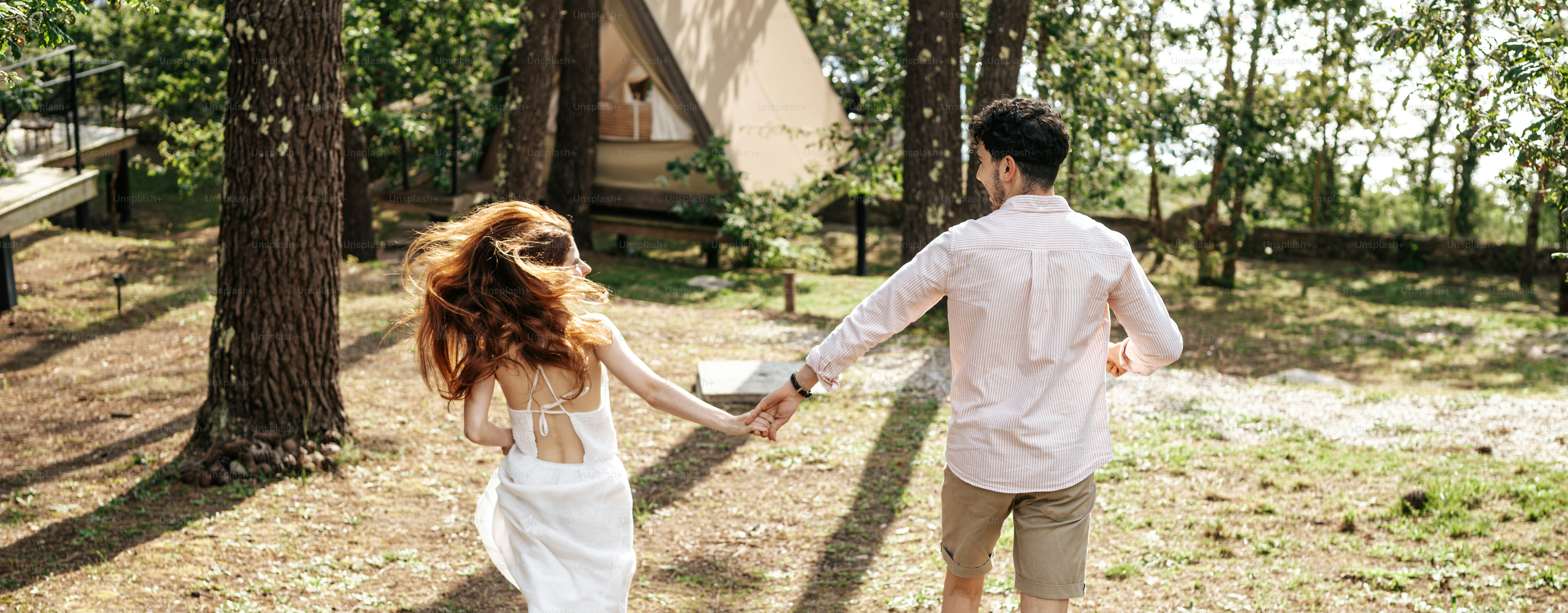 A man and a woman holding hands in the woods