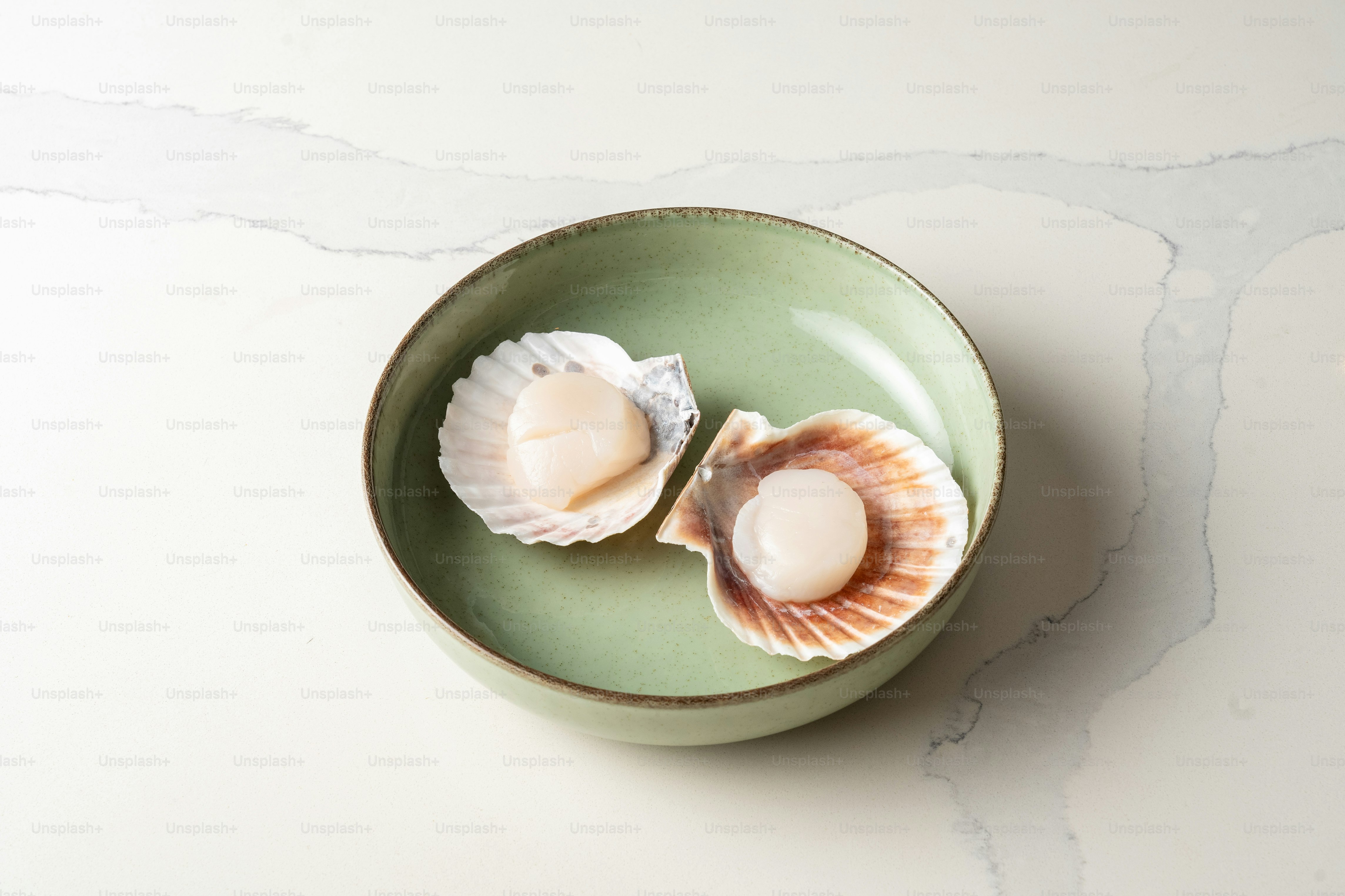 A green bowl with two seashells in it