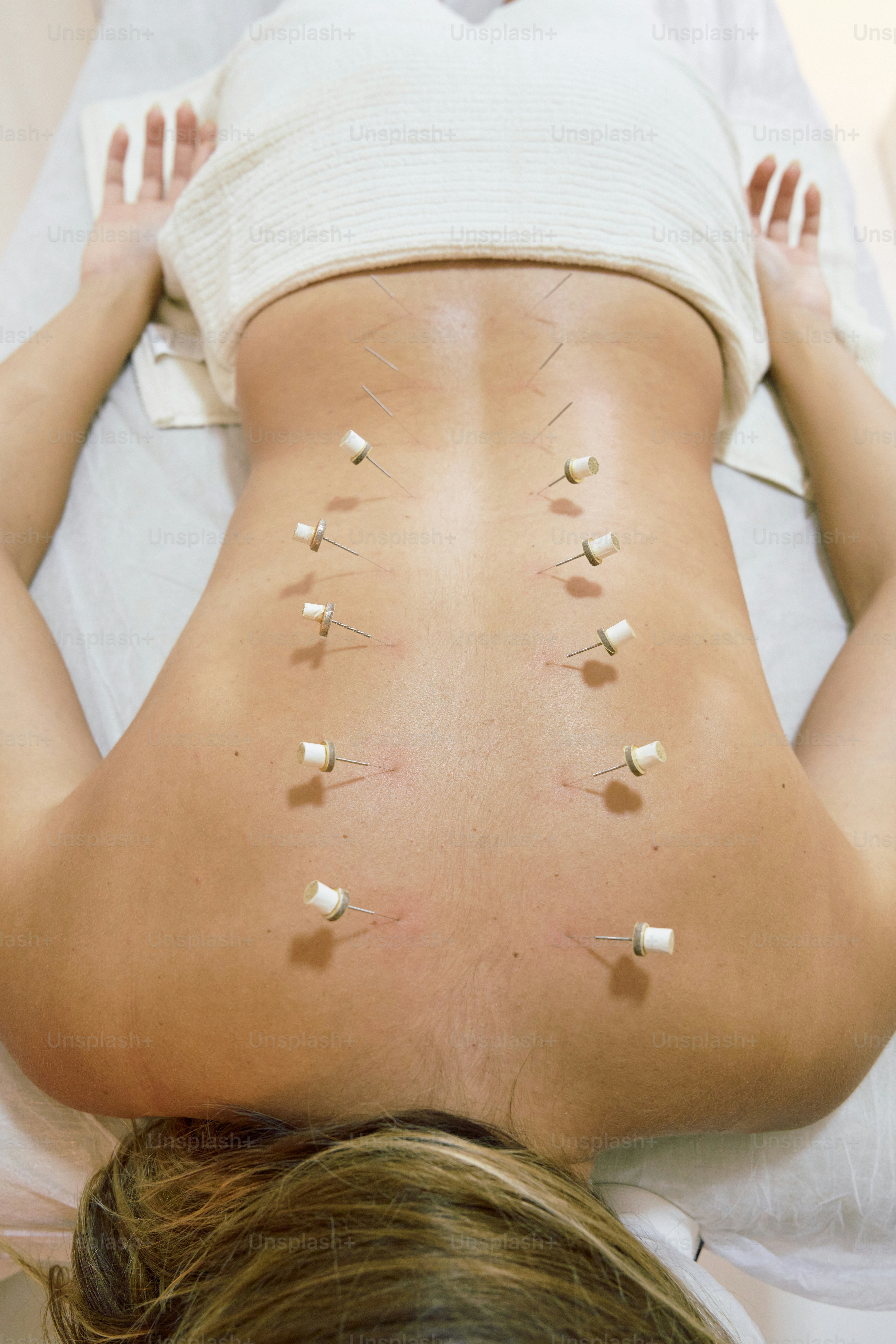 A woman laying on a bed with a lot of pins on her back