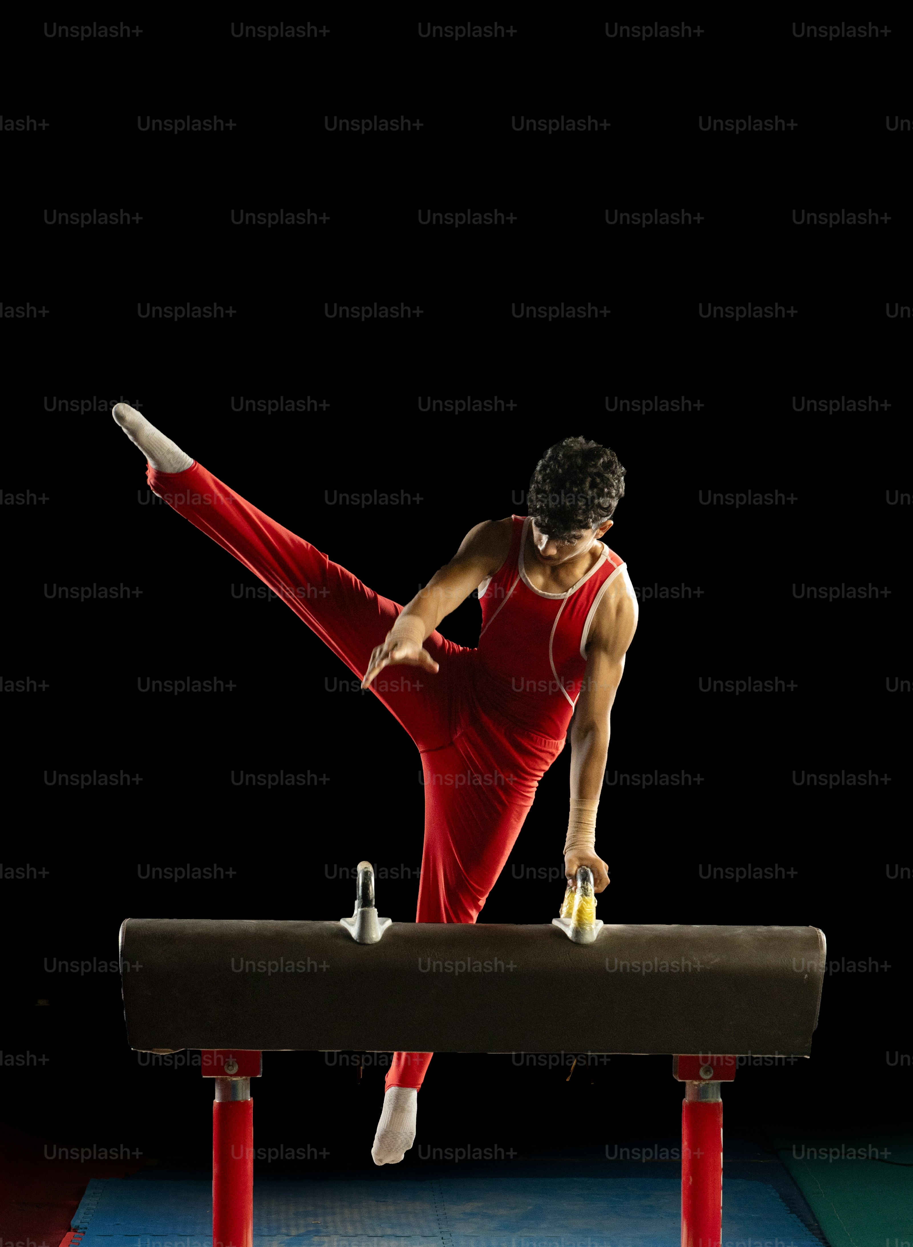 빨간 레오타드를 입은 여성이 밸런스 빔에서 쪼개지고 있습니다