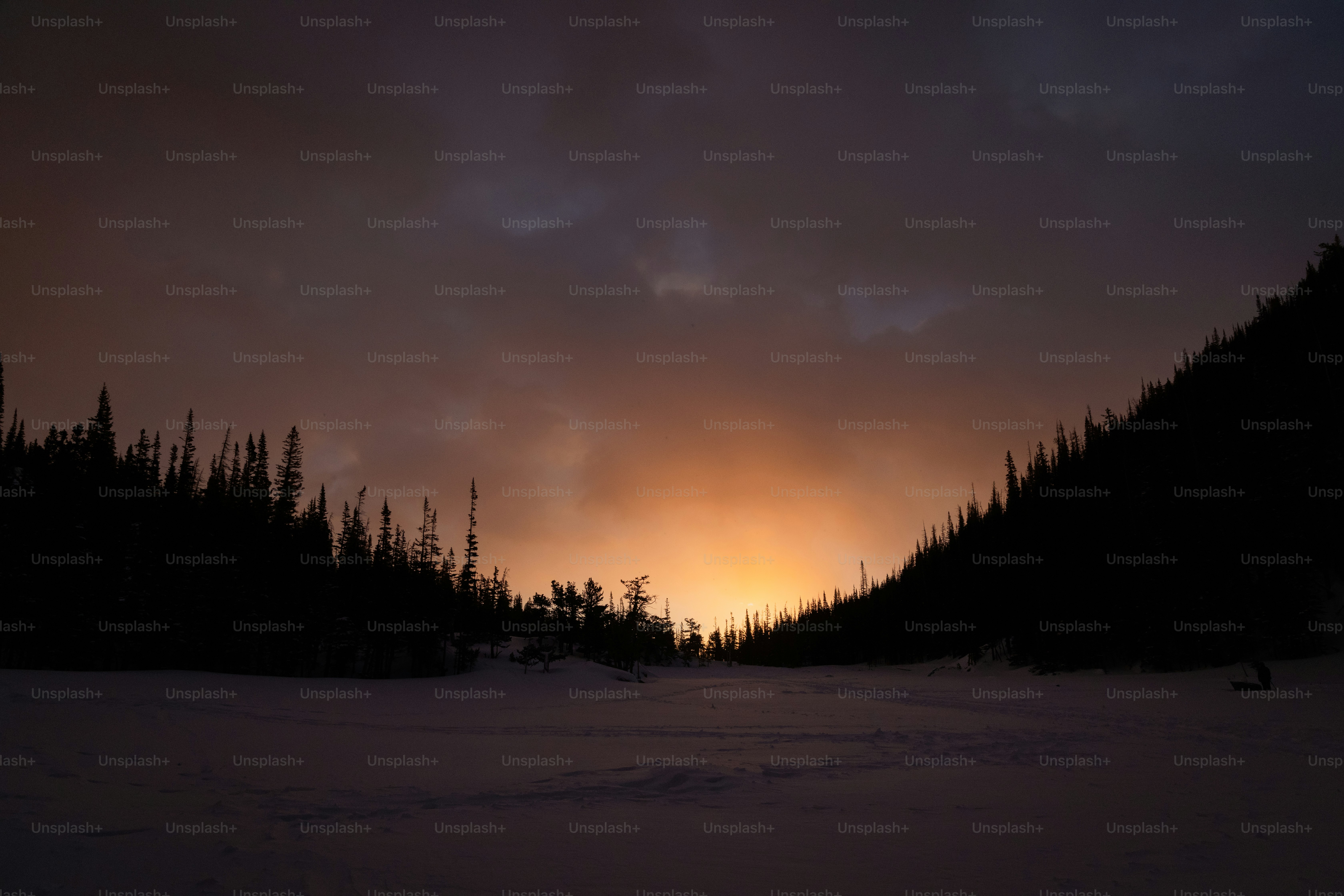 The sun is setting in the sky over the snow