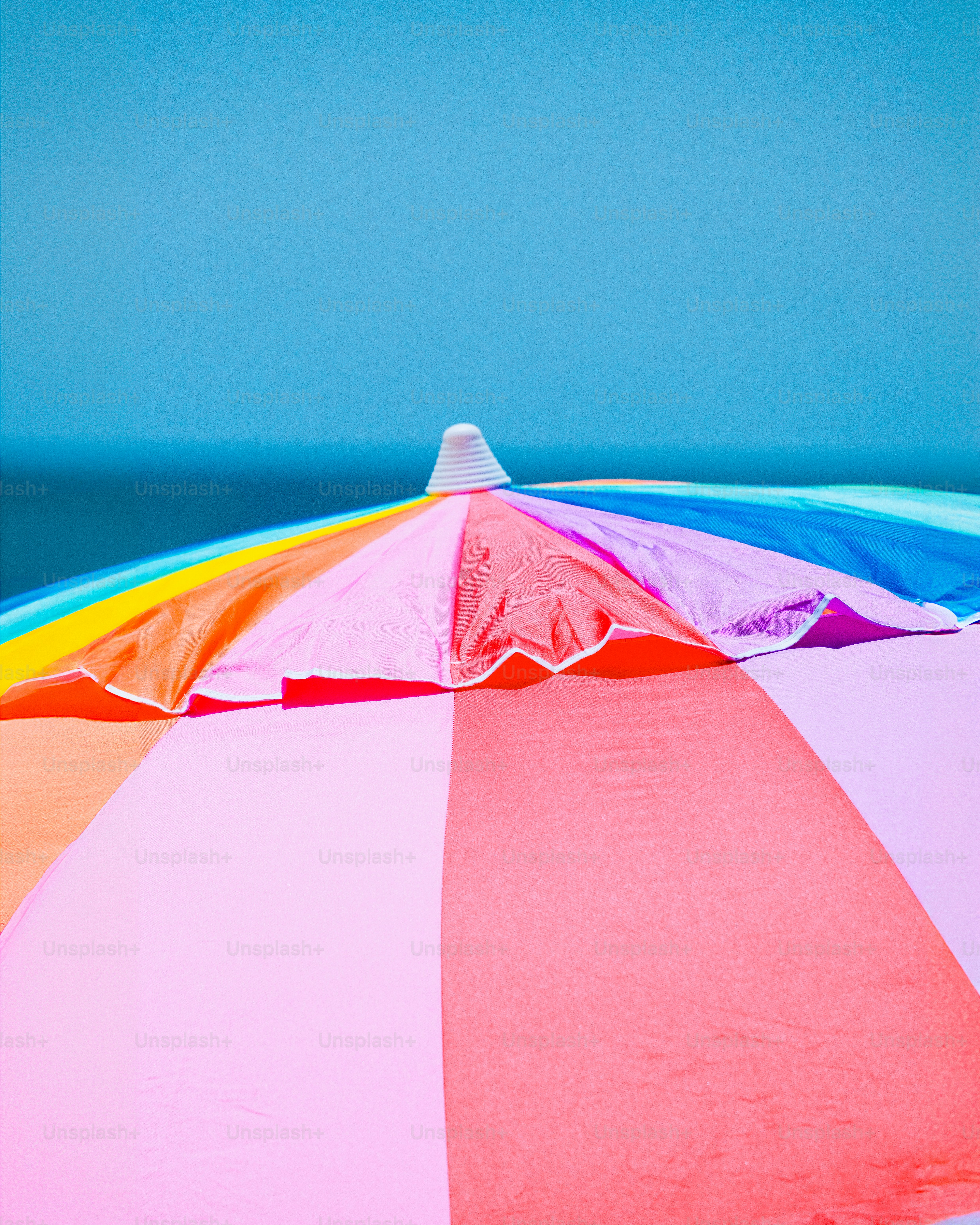 Un parasol coloré posé sur une plage de sable