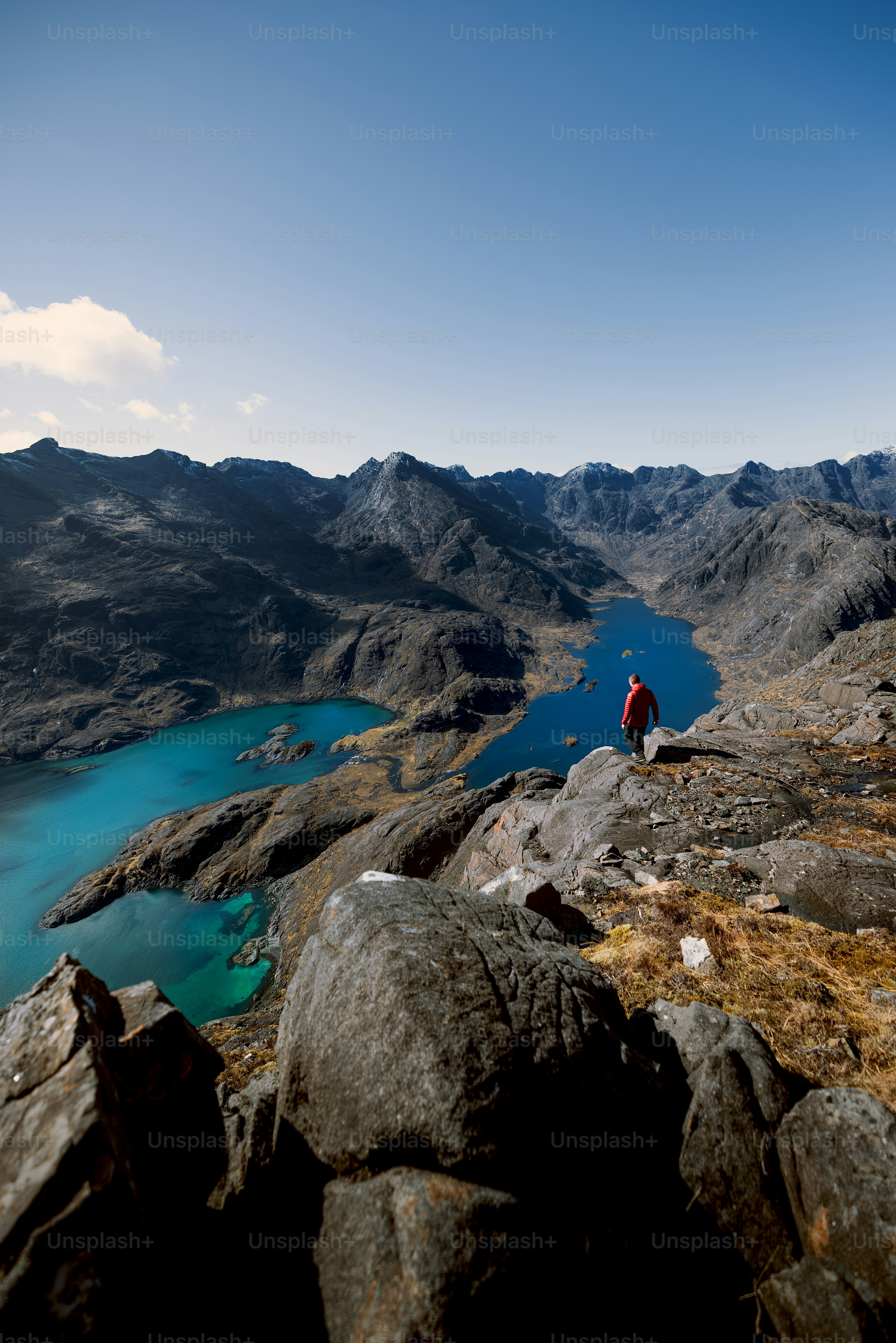 A man standing on top of a mountain next to a lake