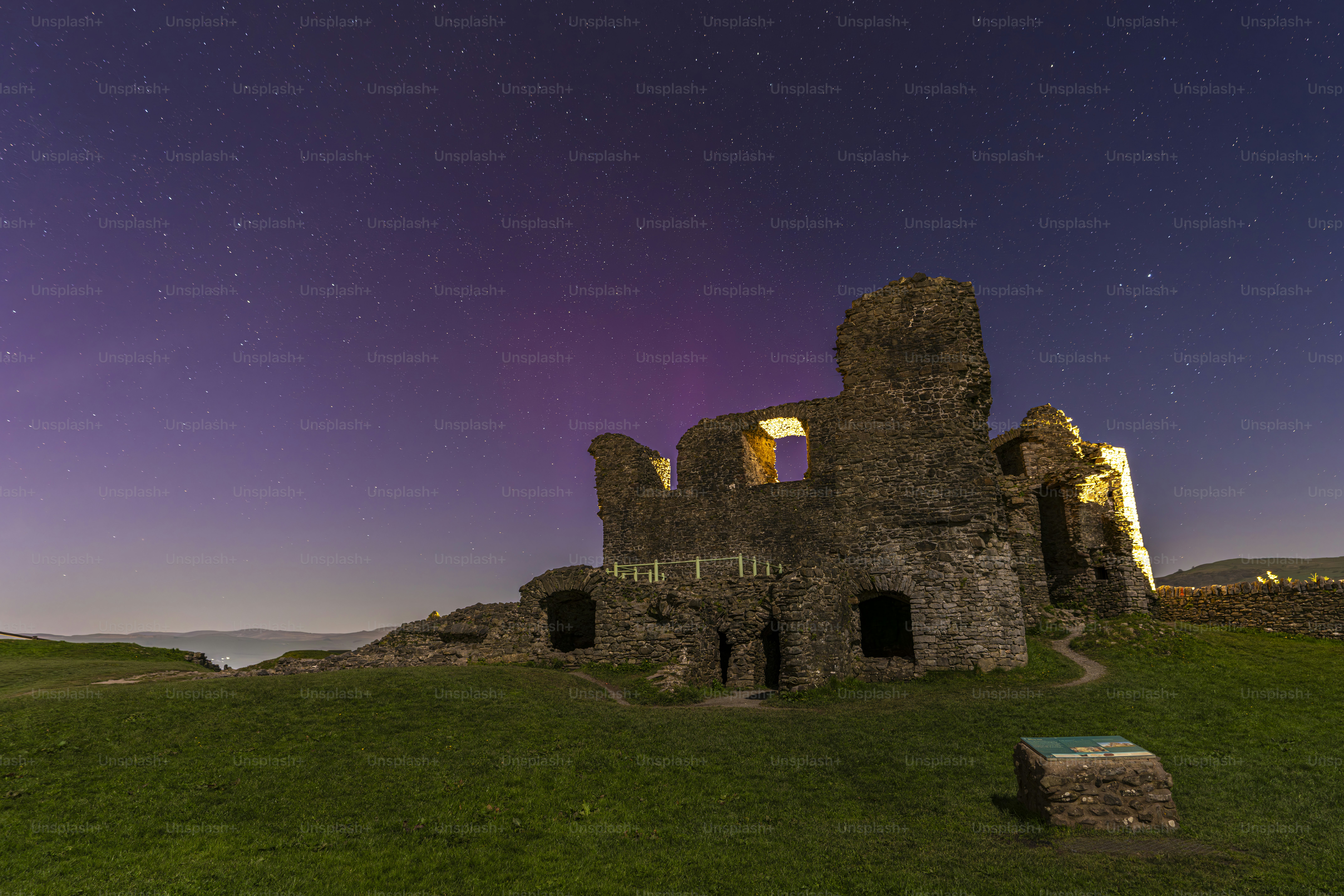 A night time photo of a castle with a purple sky