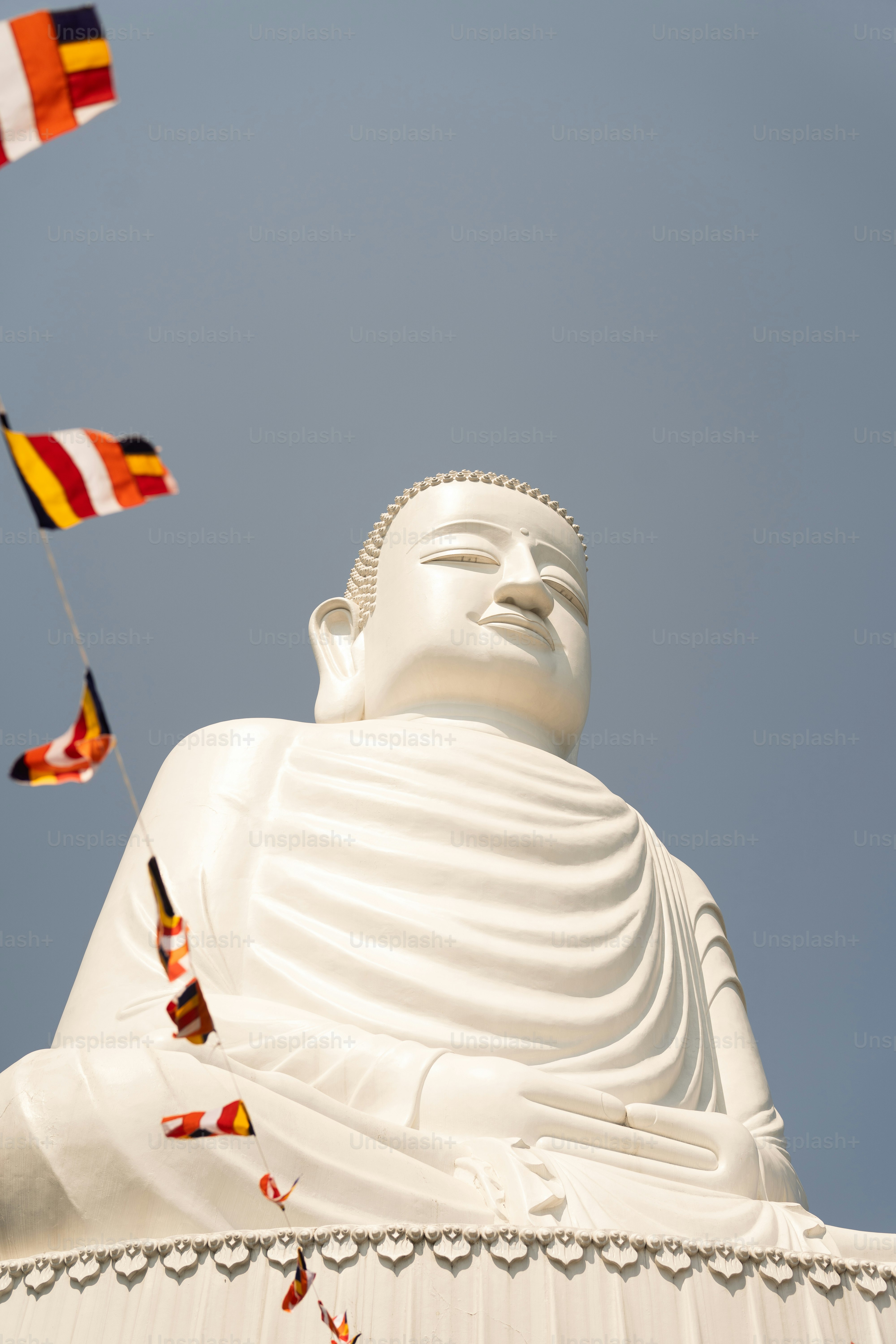 A large white buddha statue surrounded by flags