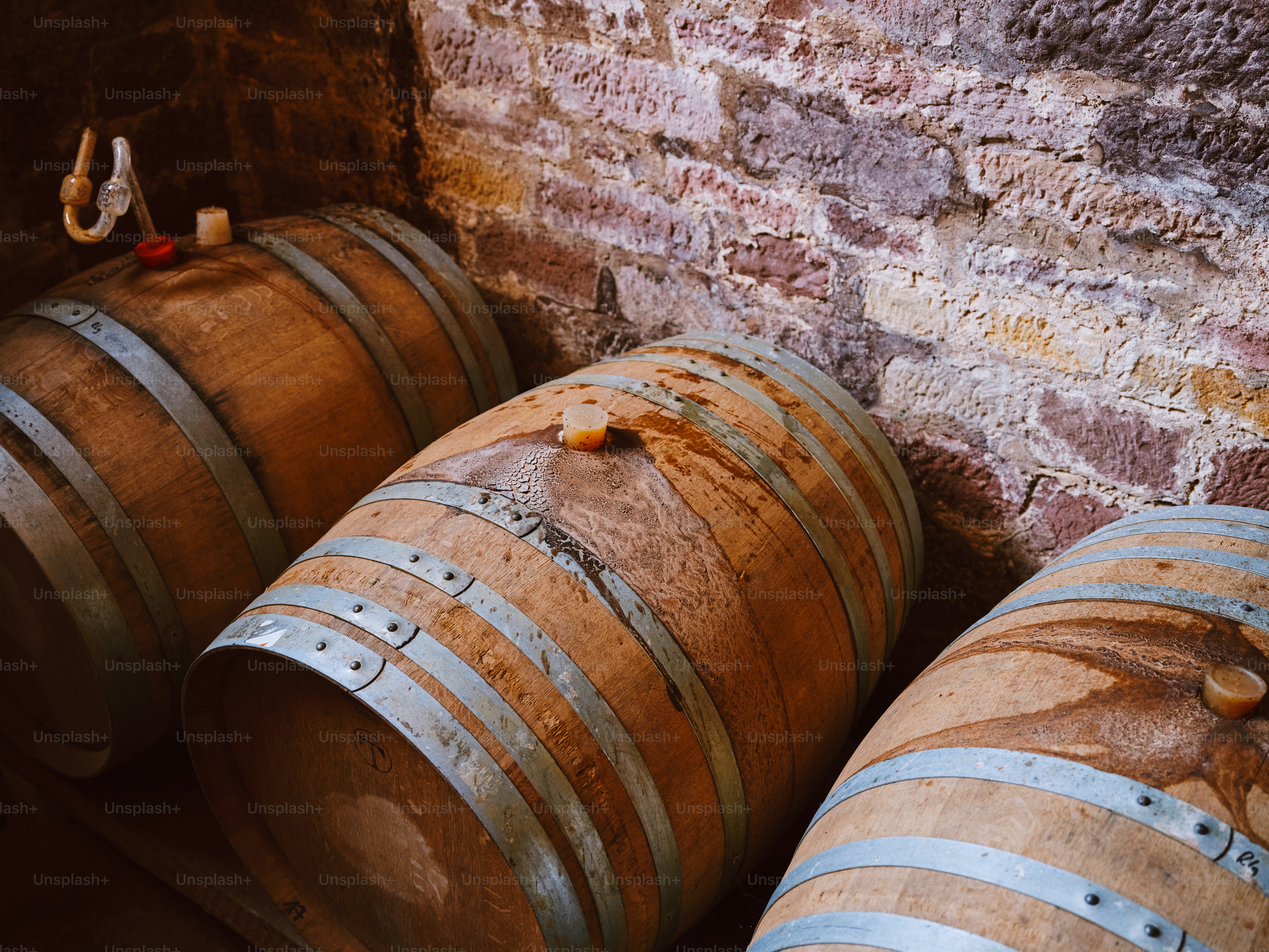 Three wine barrels lined up against a brick wall
