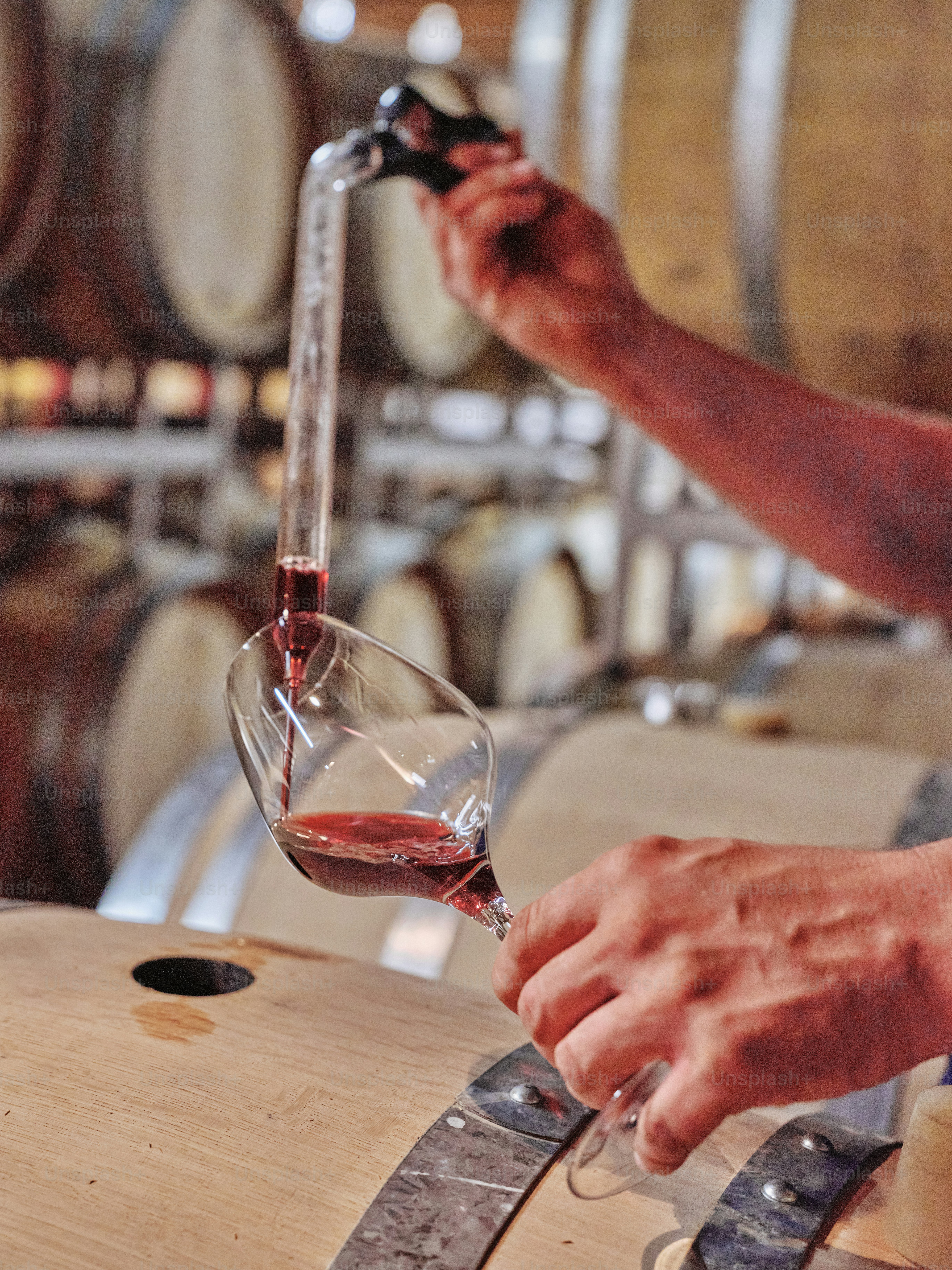 A man pouring a glass of wine into a wine barrel