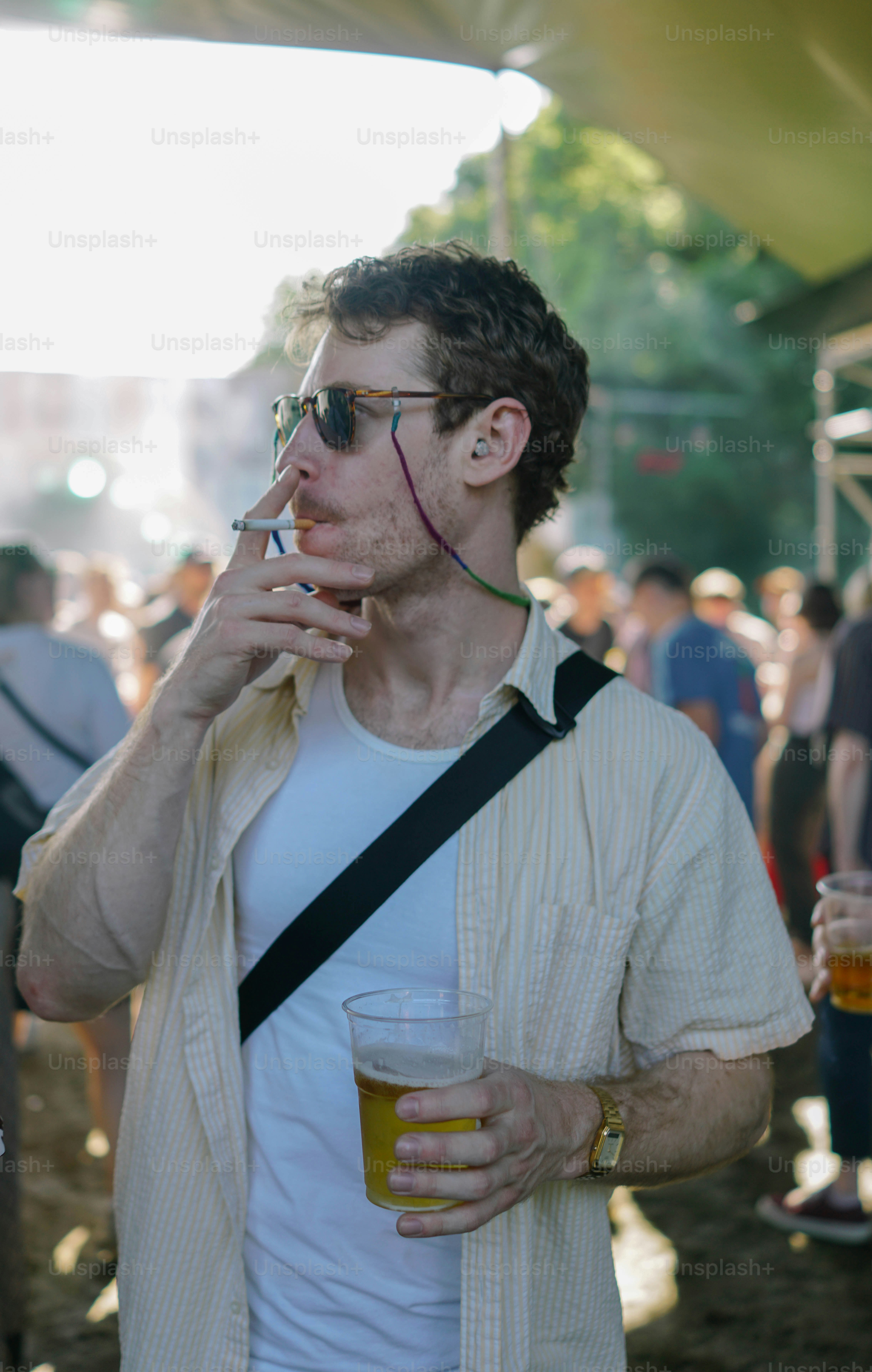 A man smoking a cigarette and drinking a beer