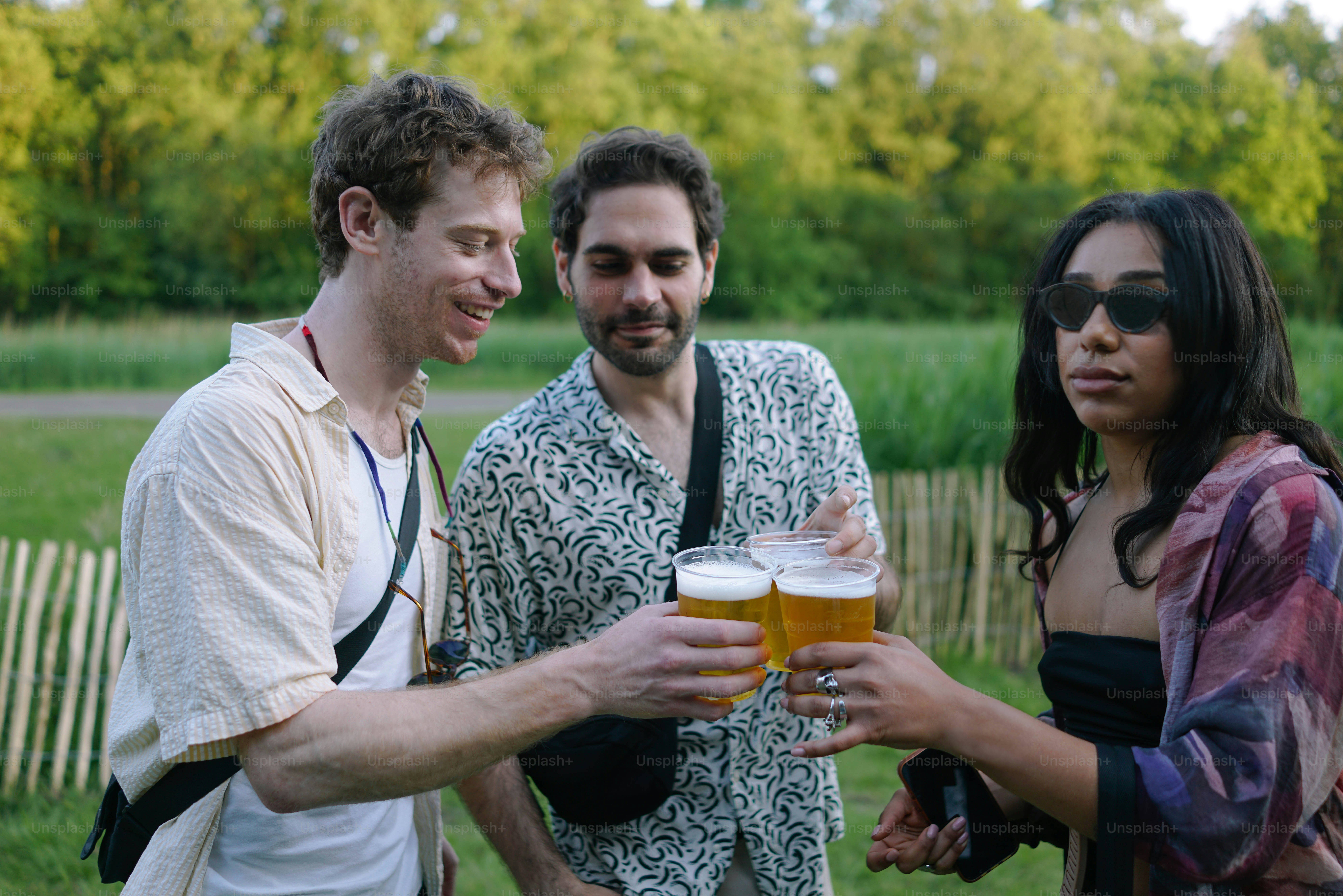A group of people standing next to each other holding glasses of beer