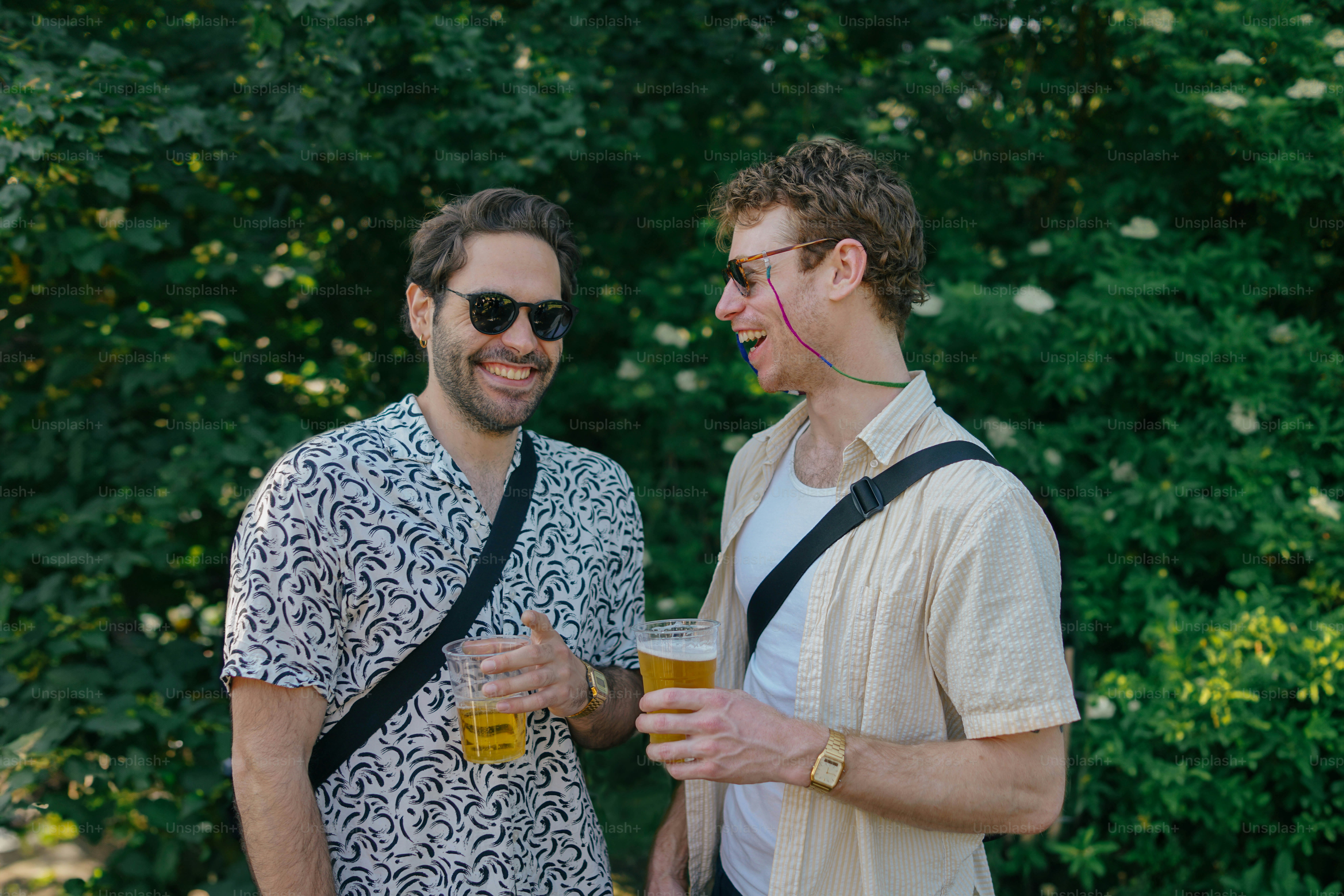 A group of people standing around each other holding glasses of beer ...
