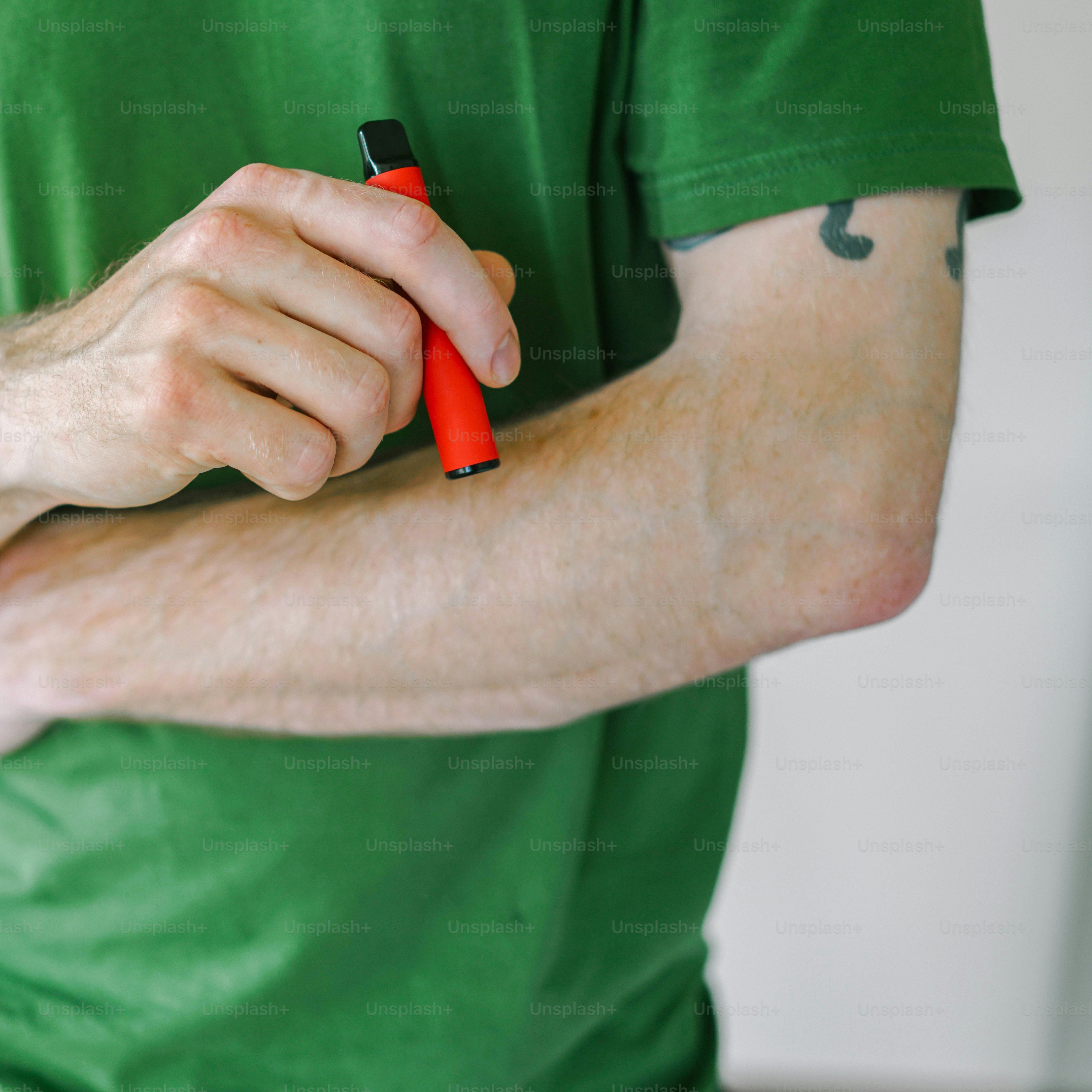 A man in a green shirt holding a red pen