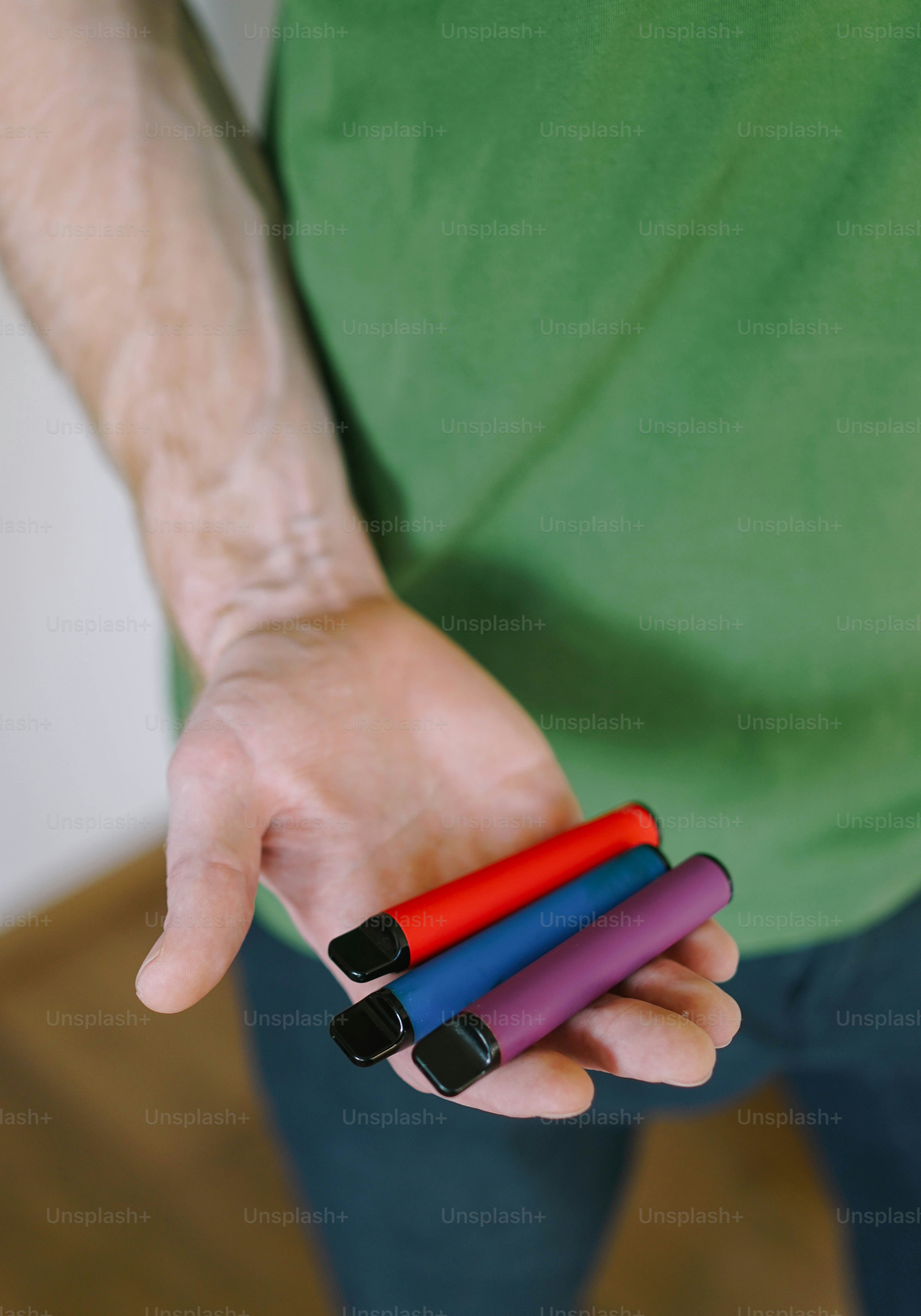 A man is holding three different colored objects in his hands