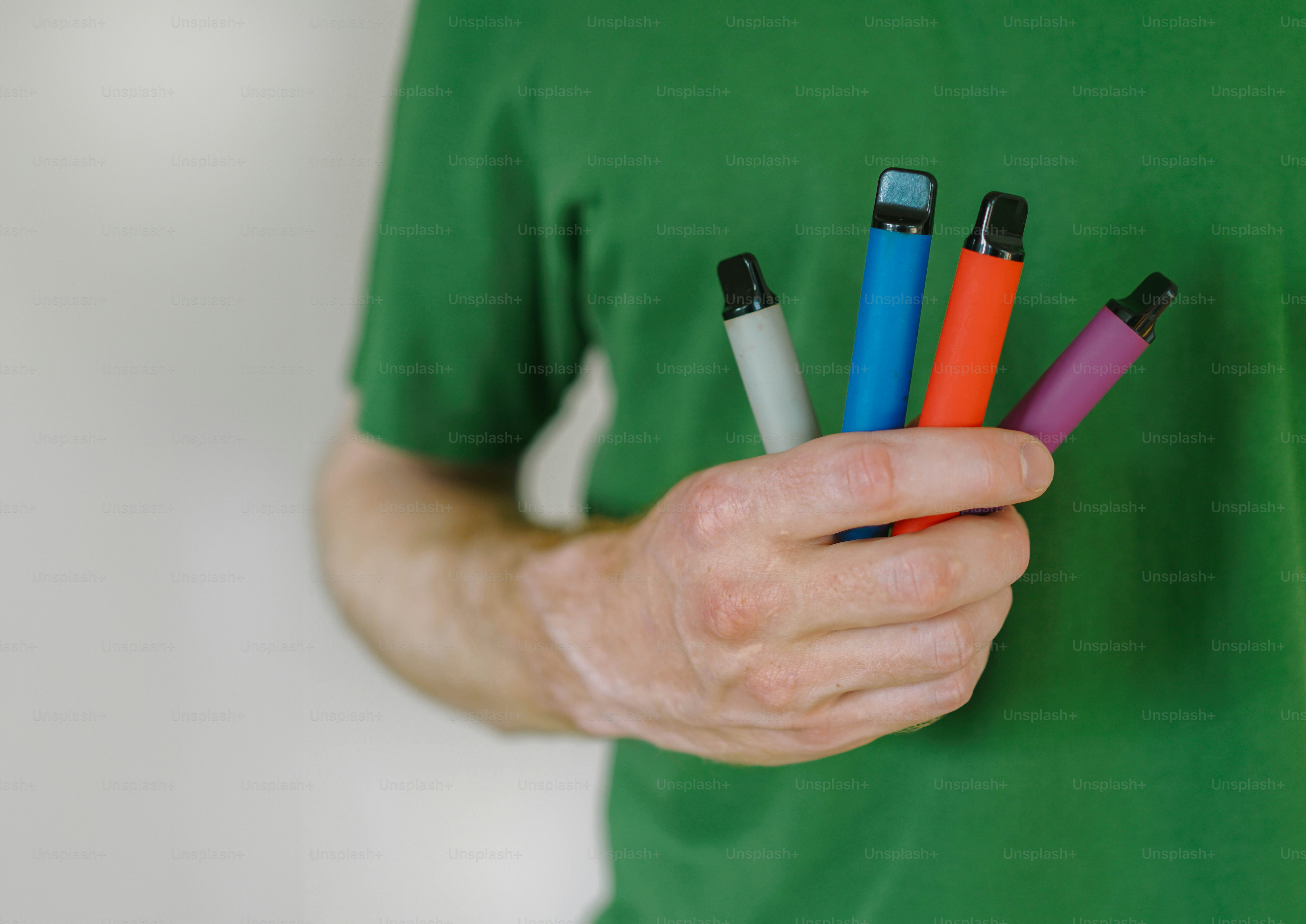 A man in a green shirt holding four electronic devices