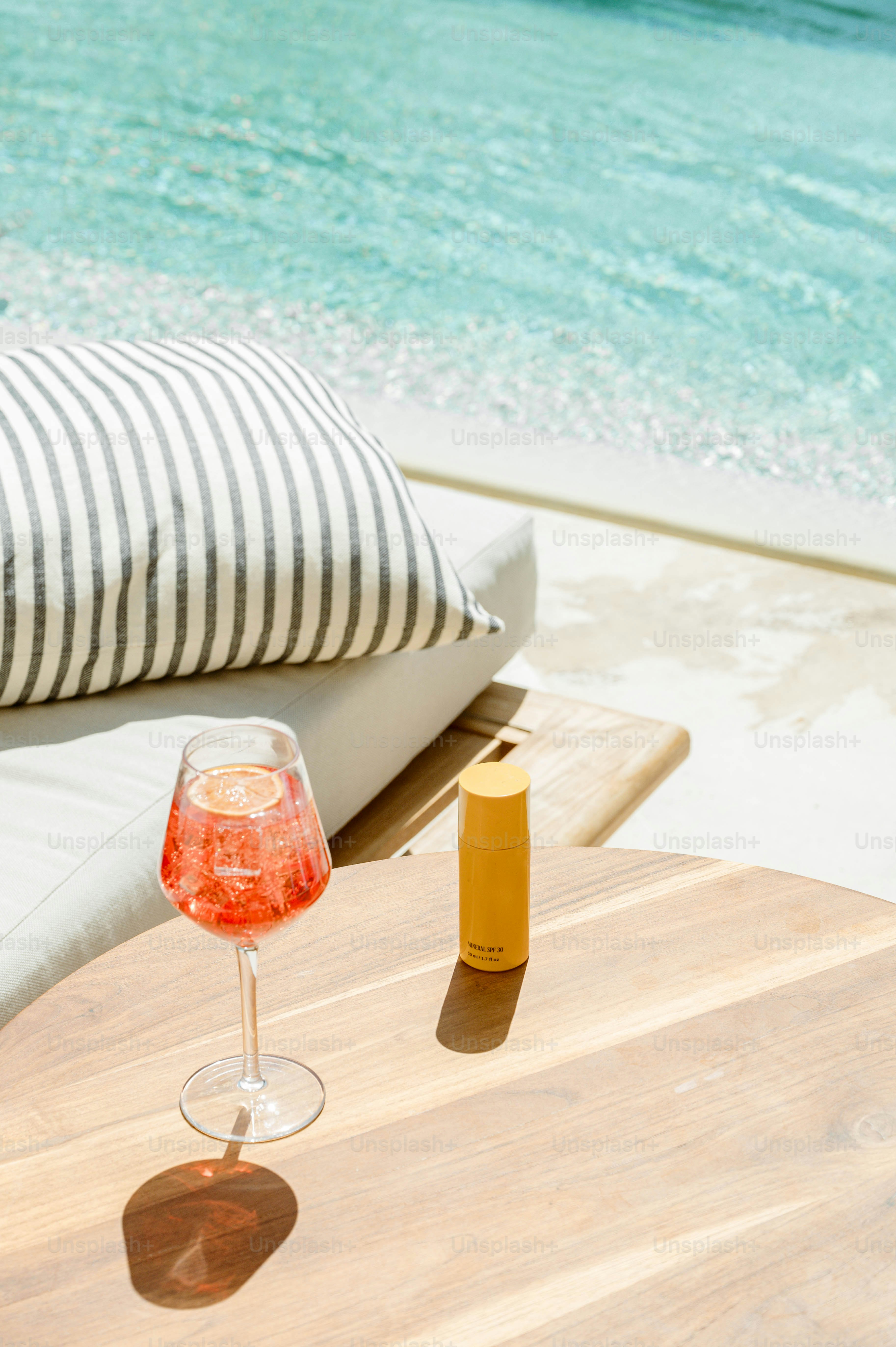 A glass of wine sitting on a wooden table next to the ocean