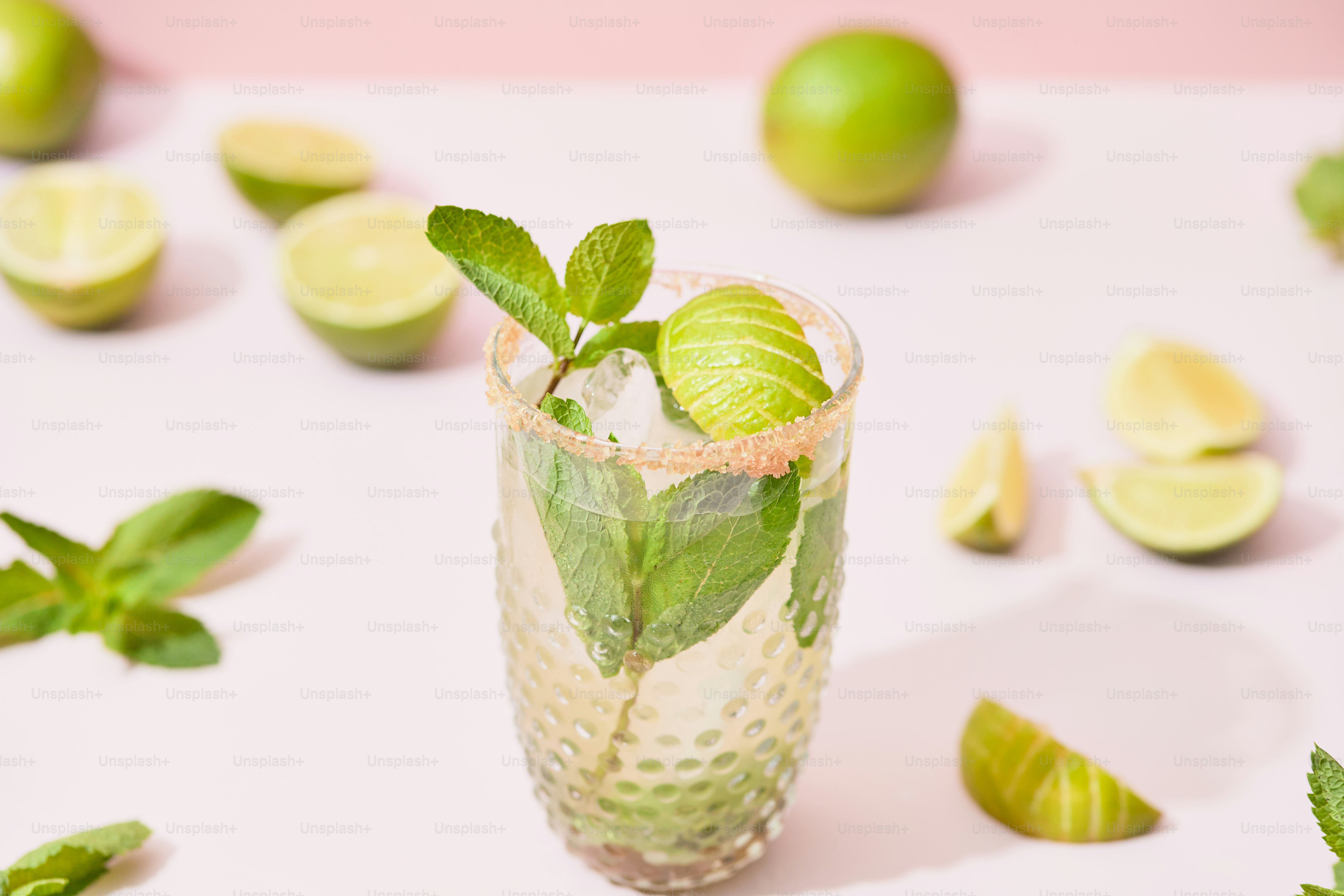 Un verre rempli d’une boisson verte entourée de citrons verts