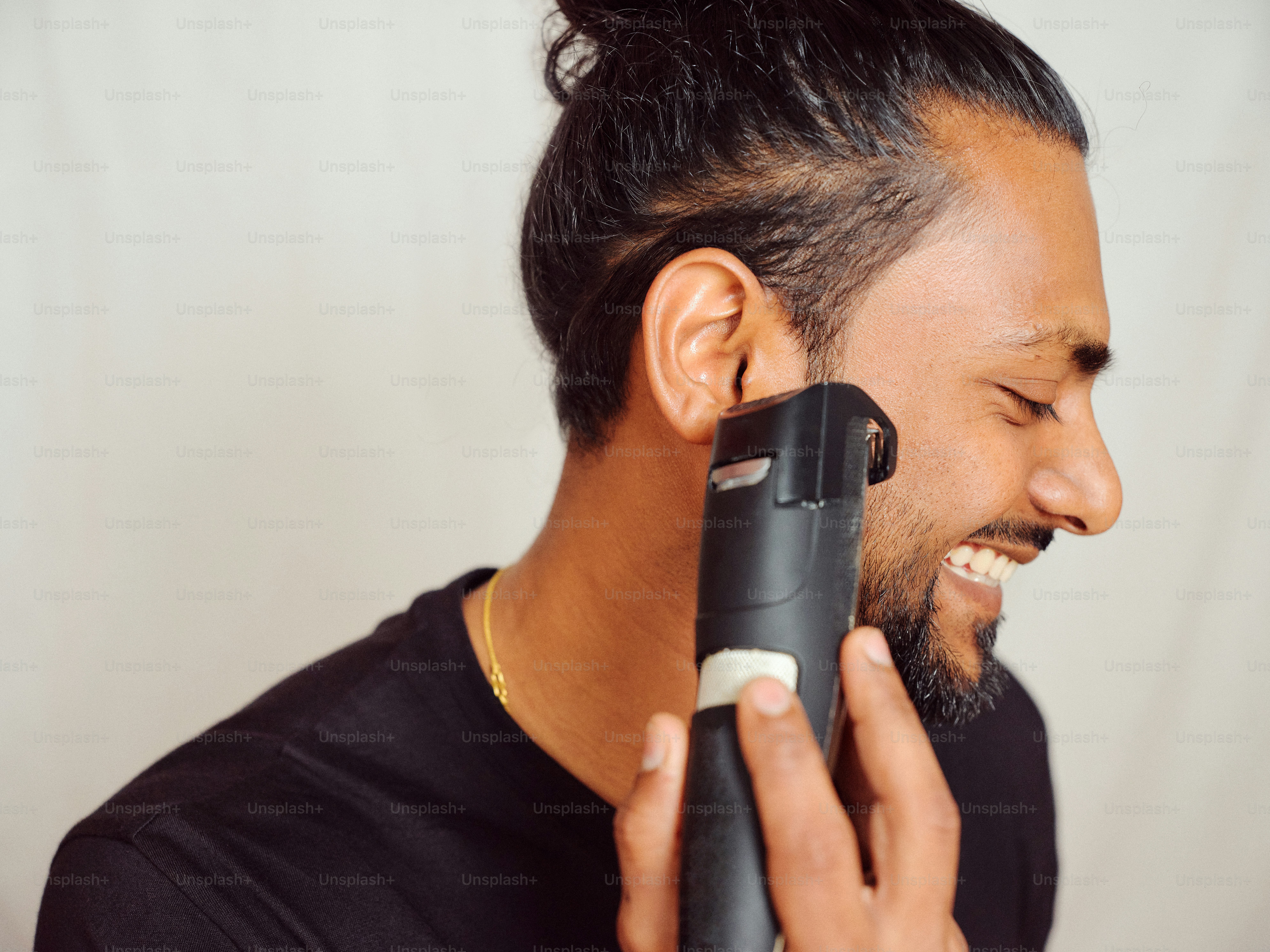 A man holding a hair dryer up to his ear