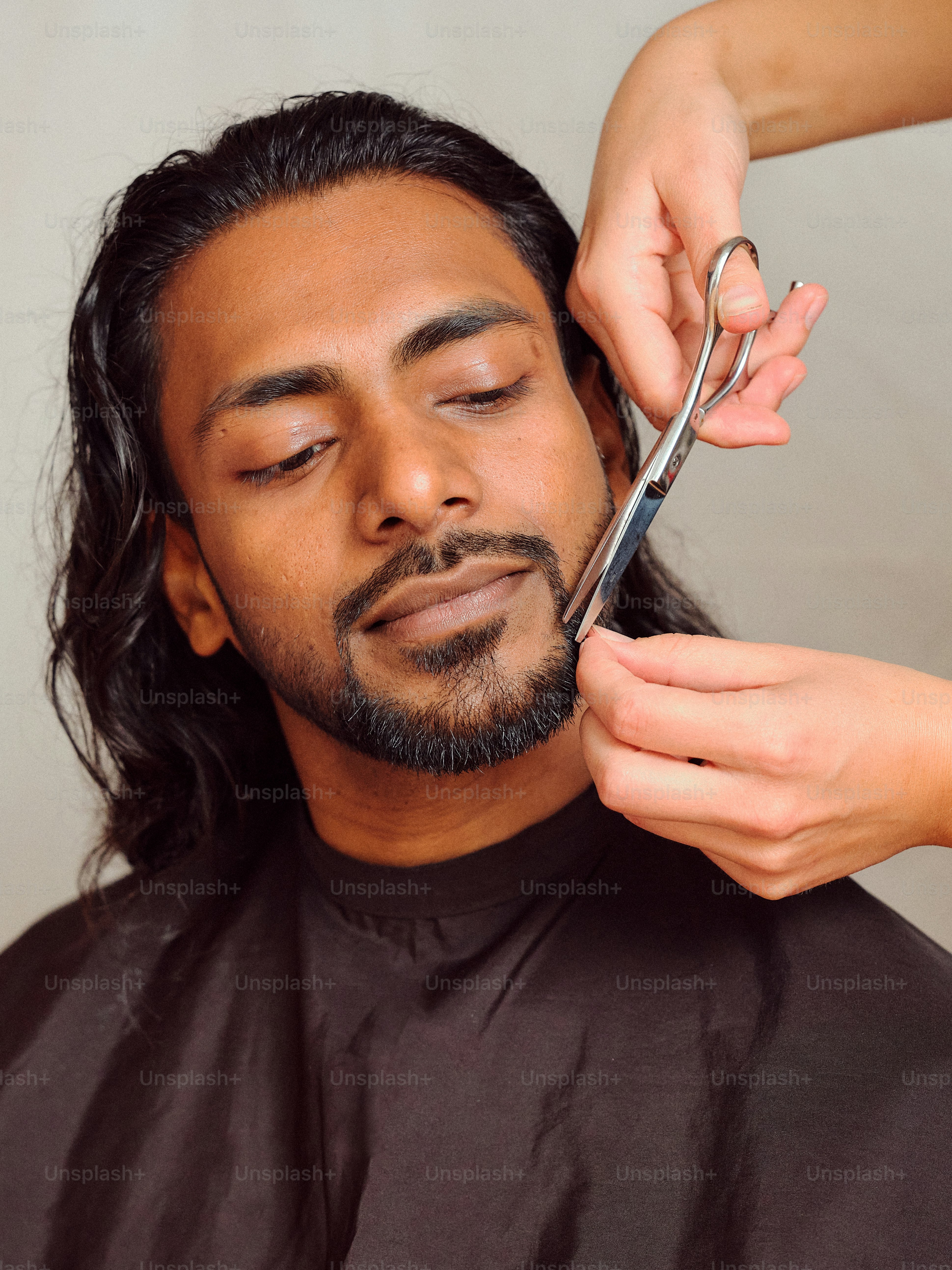 ハサミで別の男性の髪を切る男性