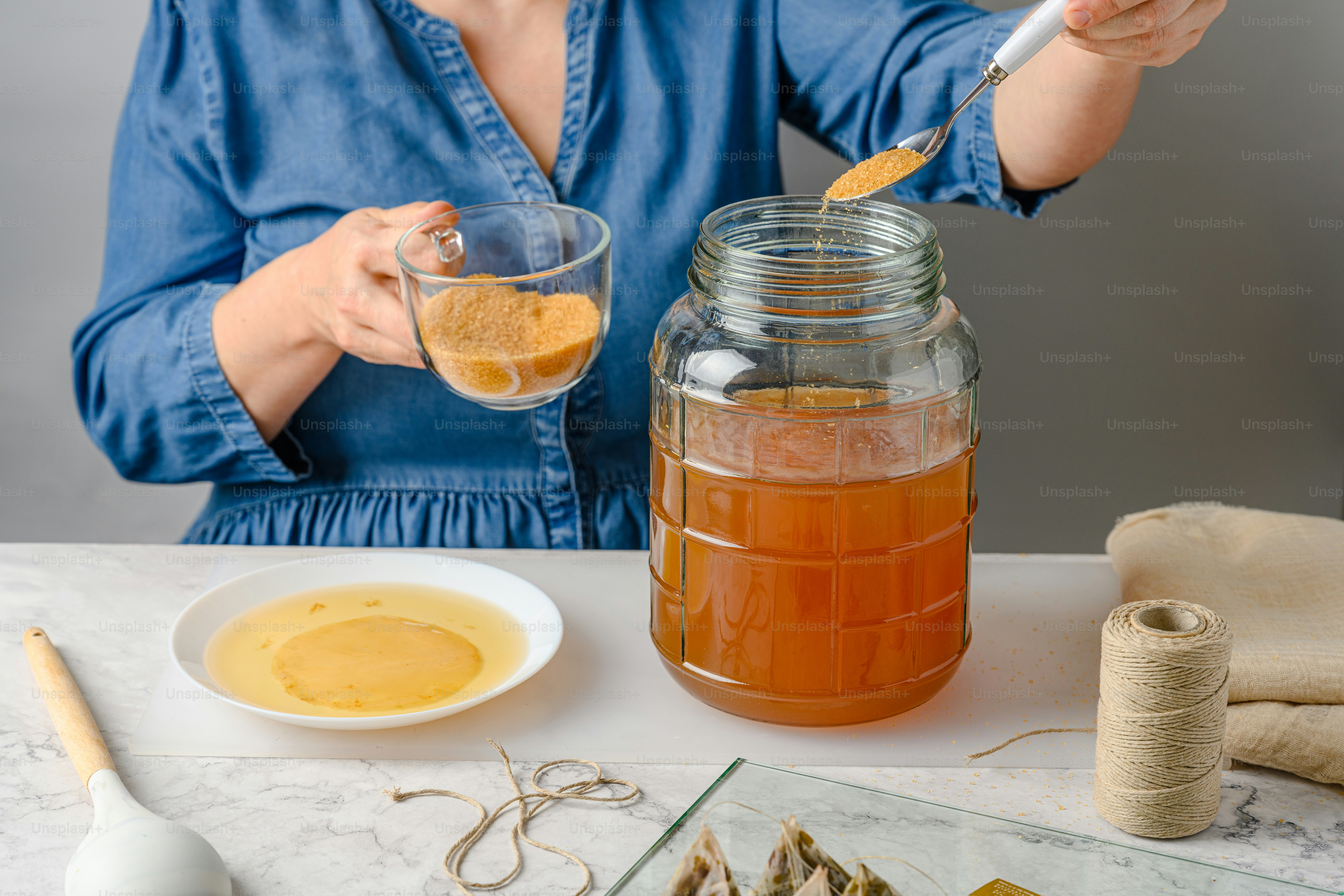 A woman holding a spoon in a jar of liquid