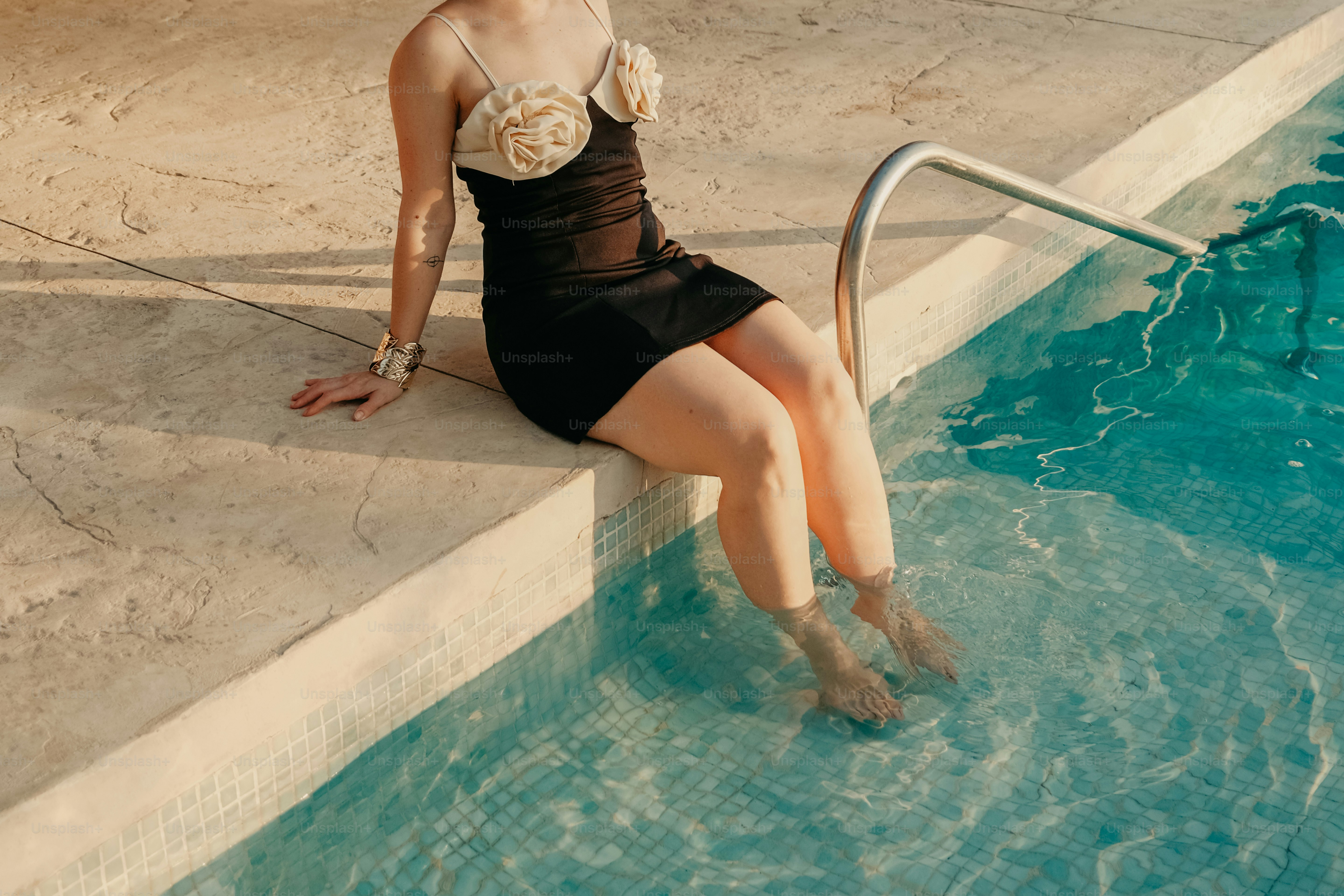 A woman sitting on the edge of a swimming pool photo – Water Image on ...