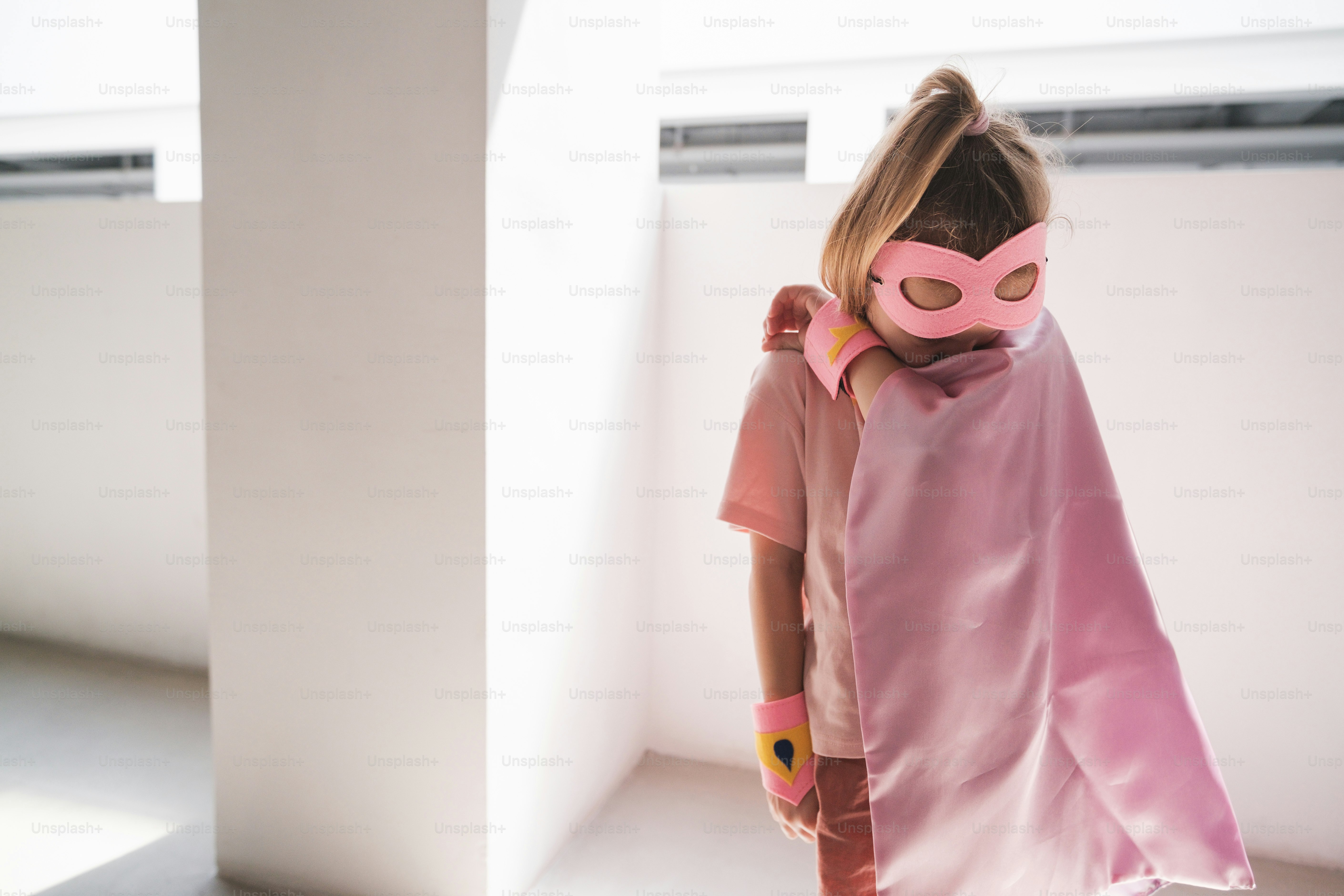 A little girl wearing a pink mask and pink dress