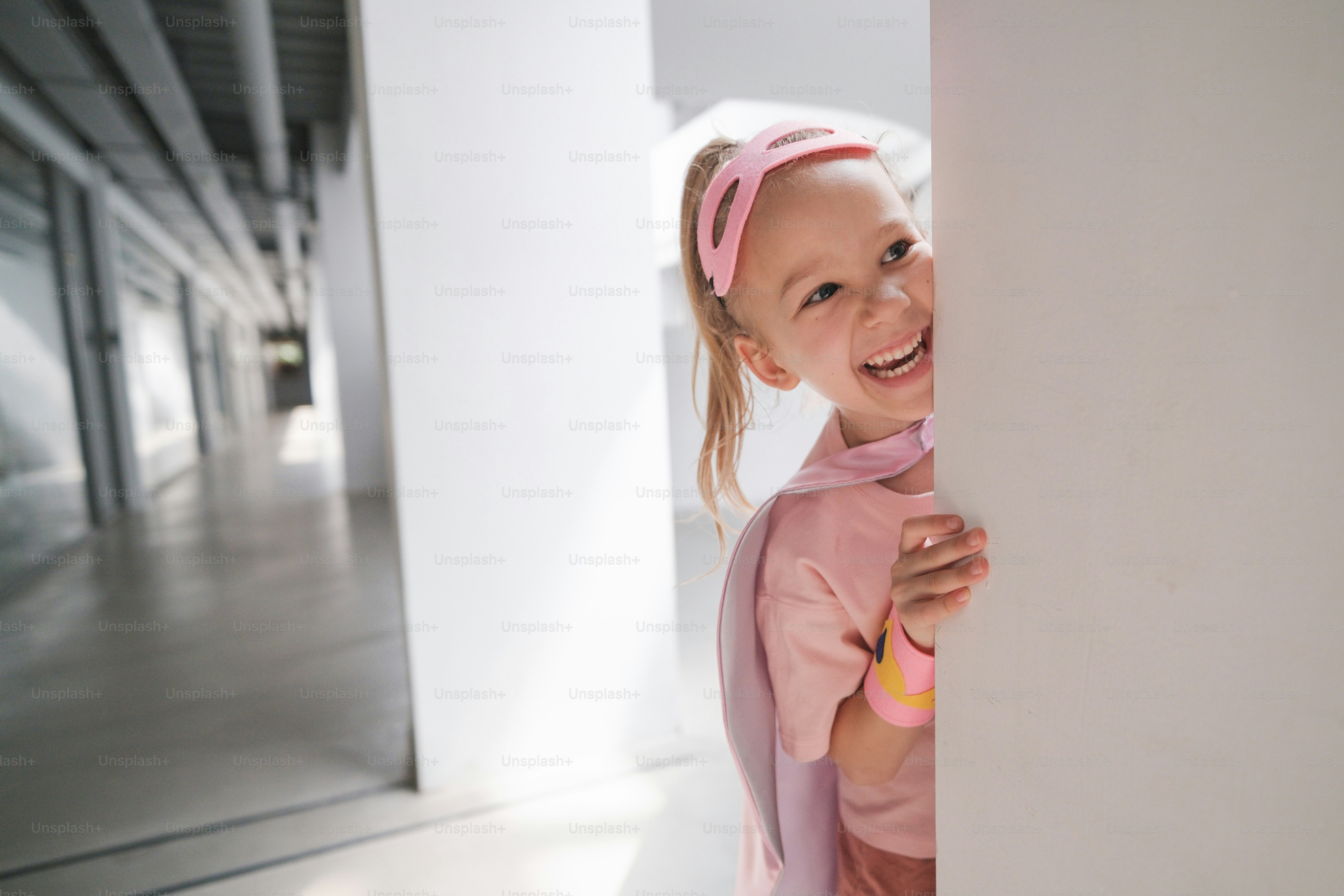 A little girl is peeking out from behind a wall