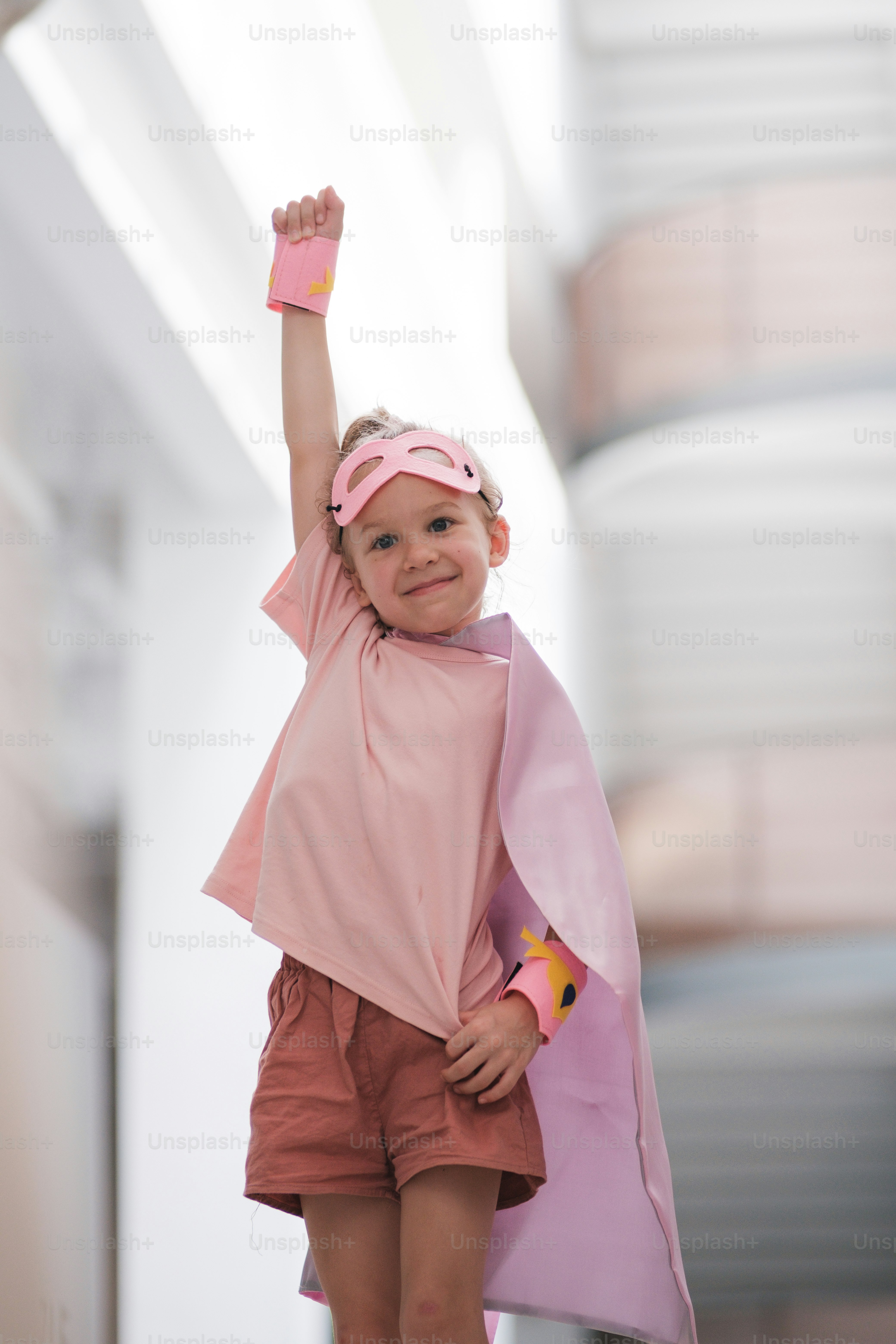A little girl wearing a pink cape and pink shoes