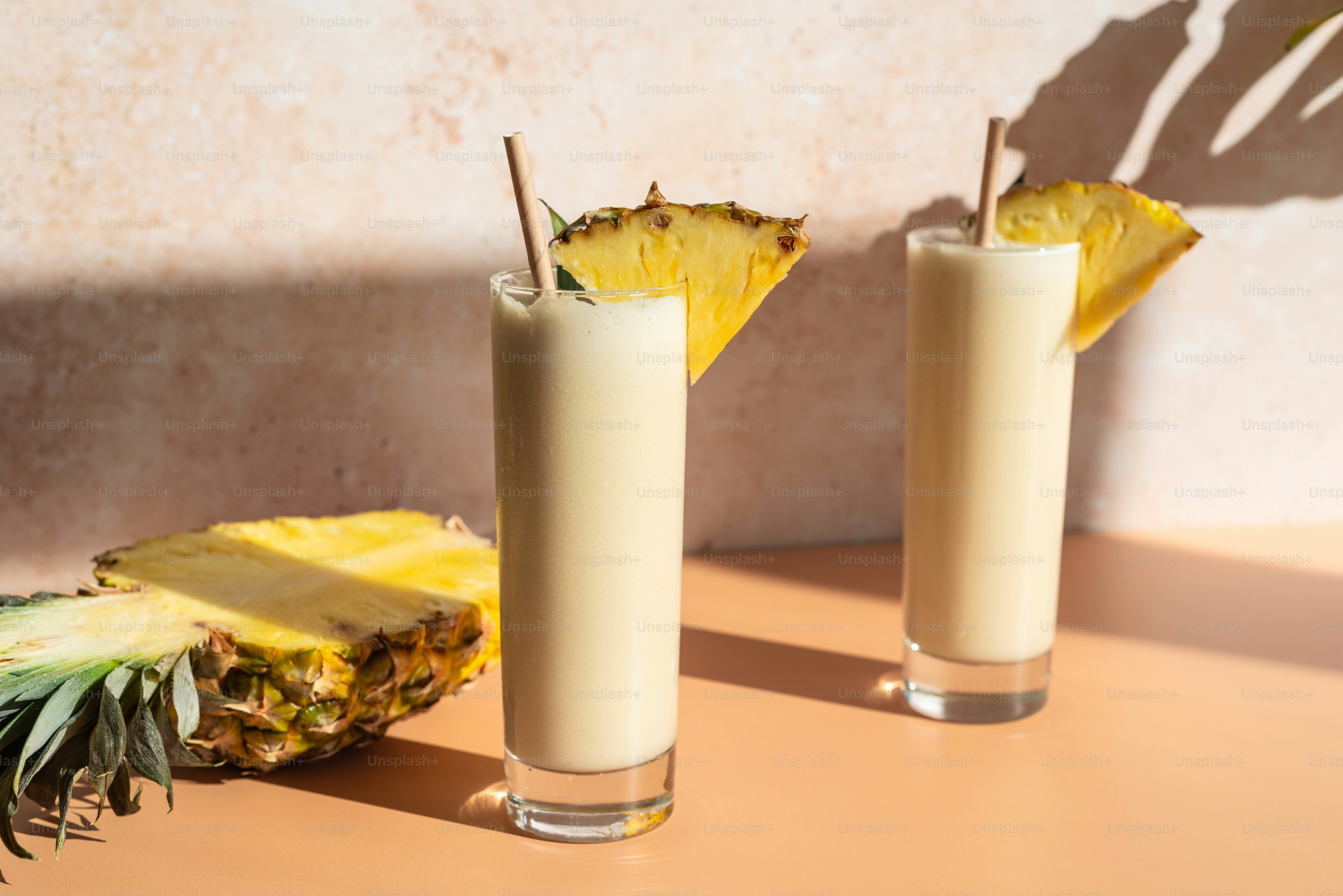 Ein paar mit Milch gefüllte Gläser neben einer Ananas