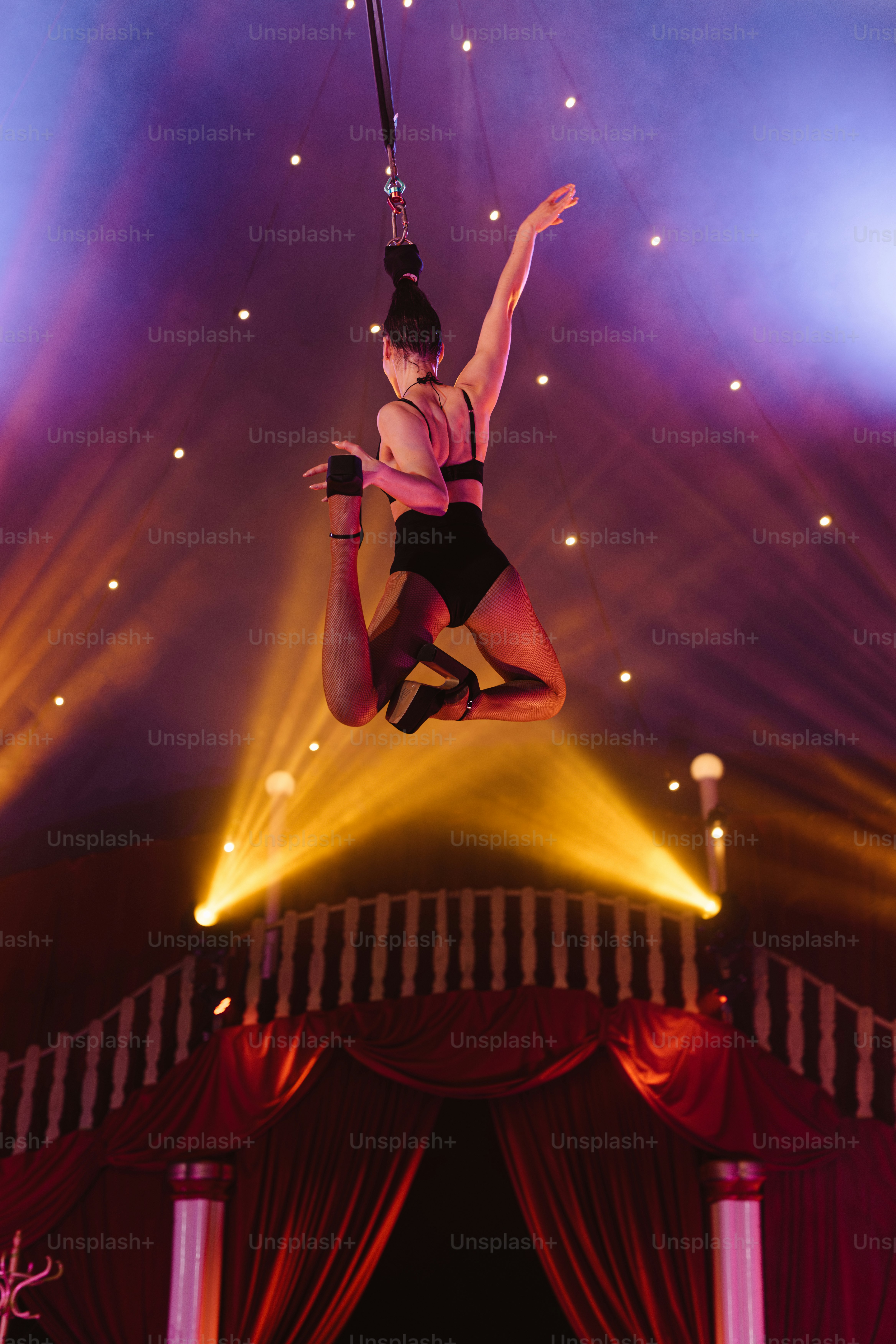 ポールの上で演技する黒いレオタード姿の女性