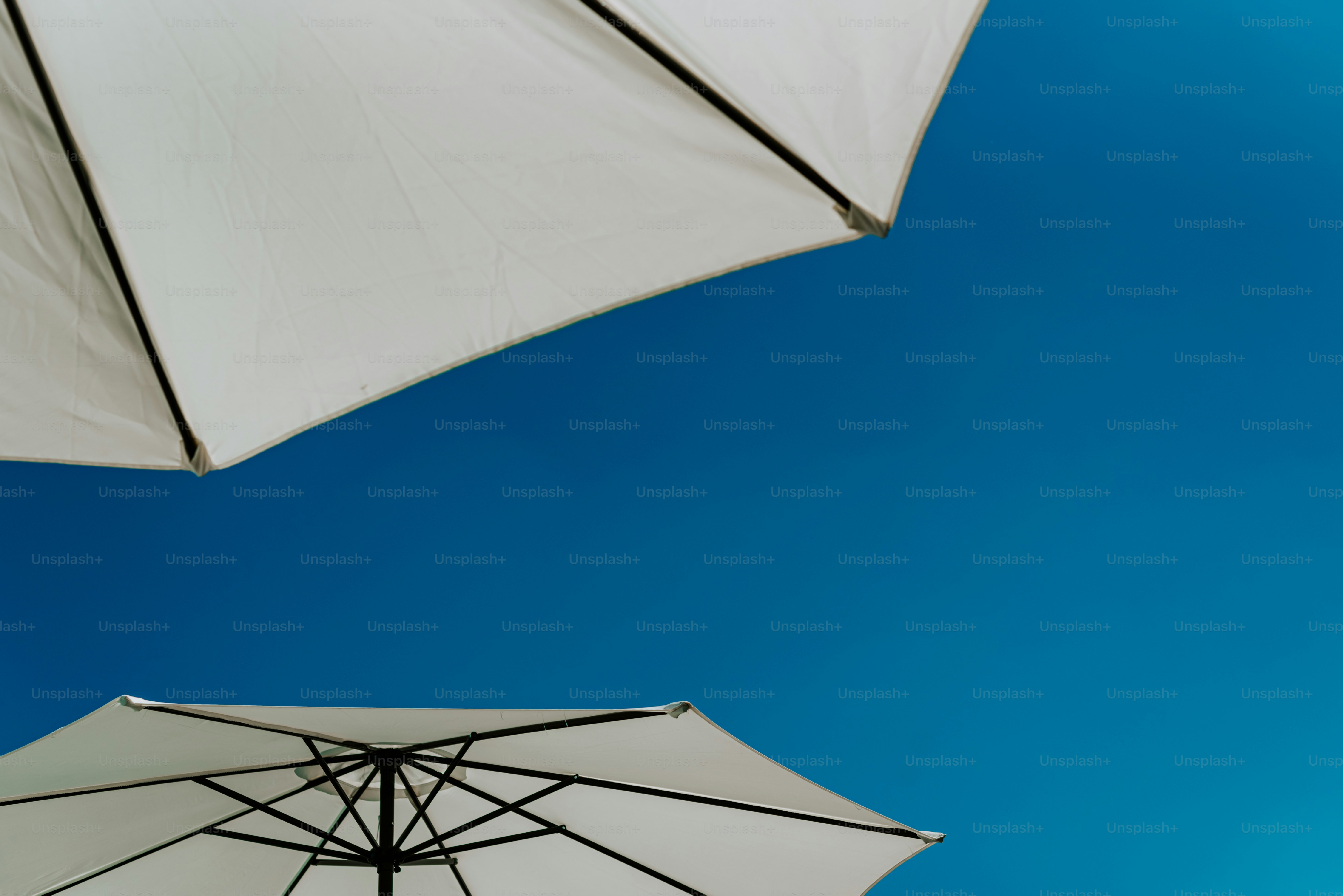 Two white umbrellas with a blue sky in the background