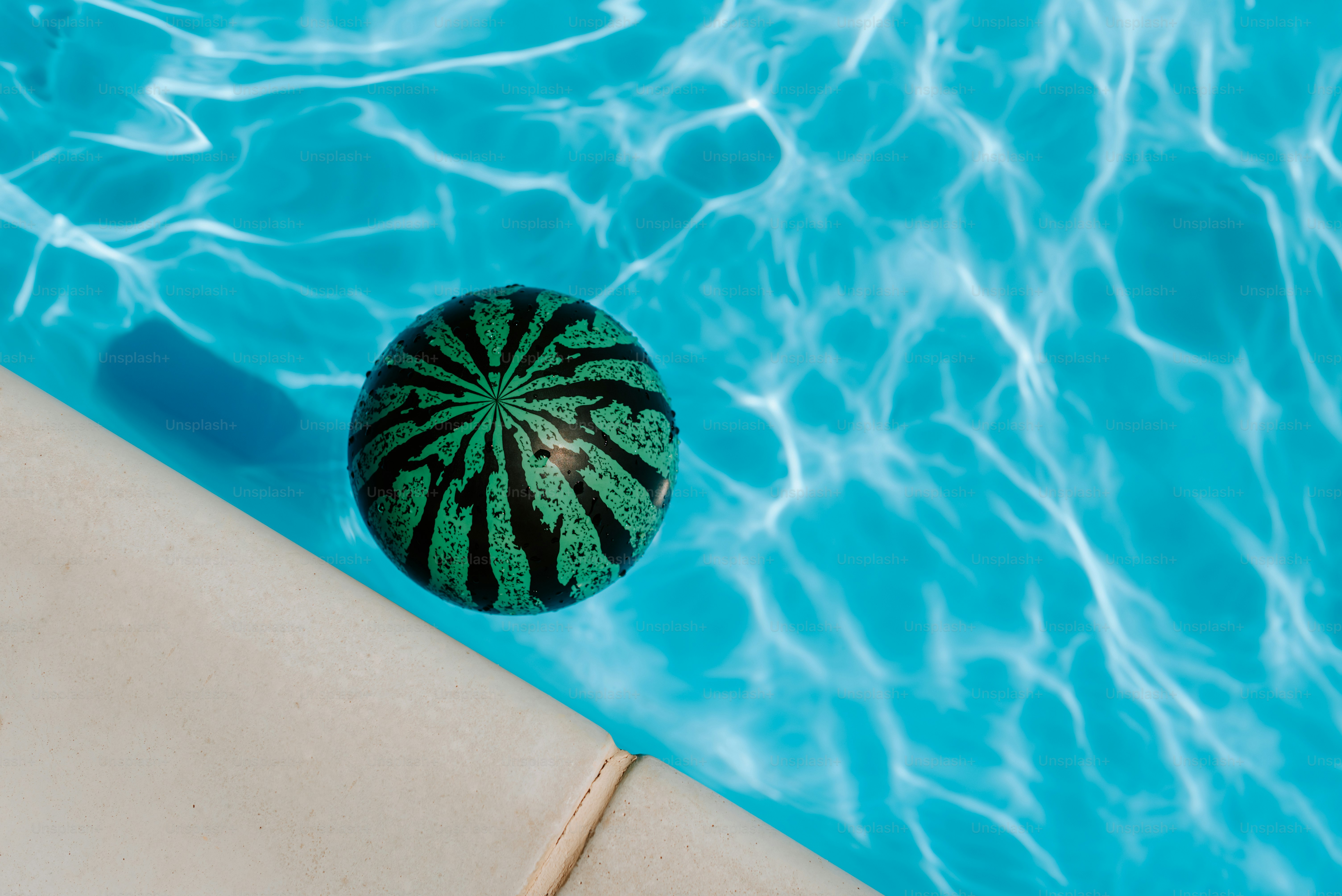 Ein grüner Ball sitzt am Rand eines Schwimmbads