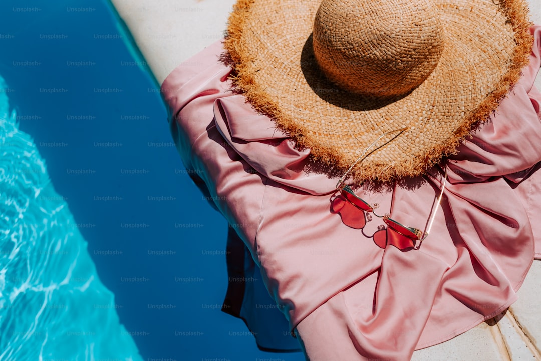 A woman in a pink dress and a straw hat sitting on a boat