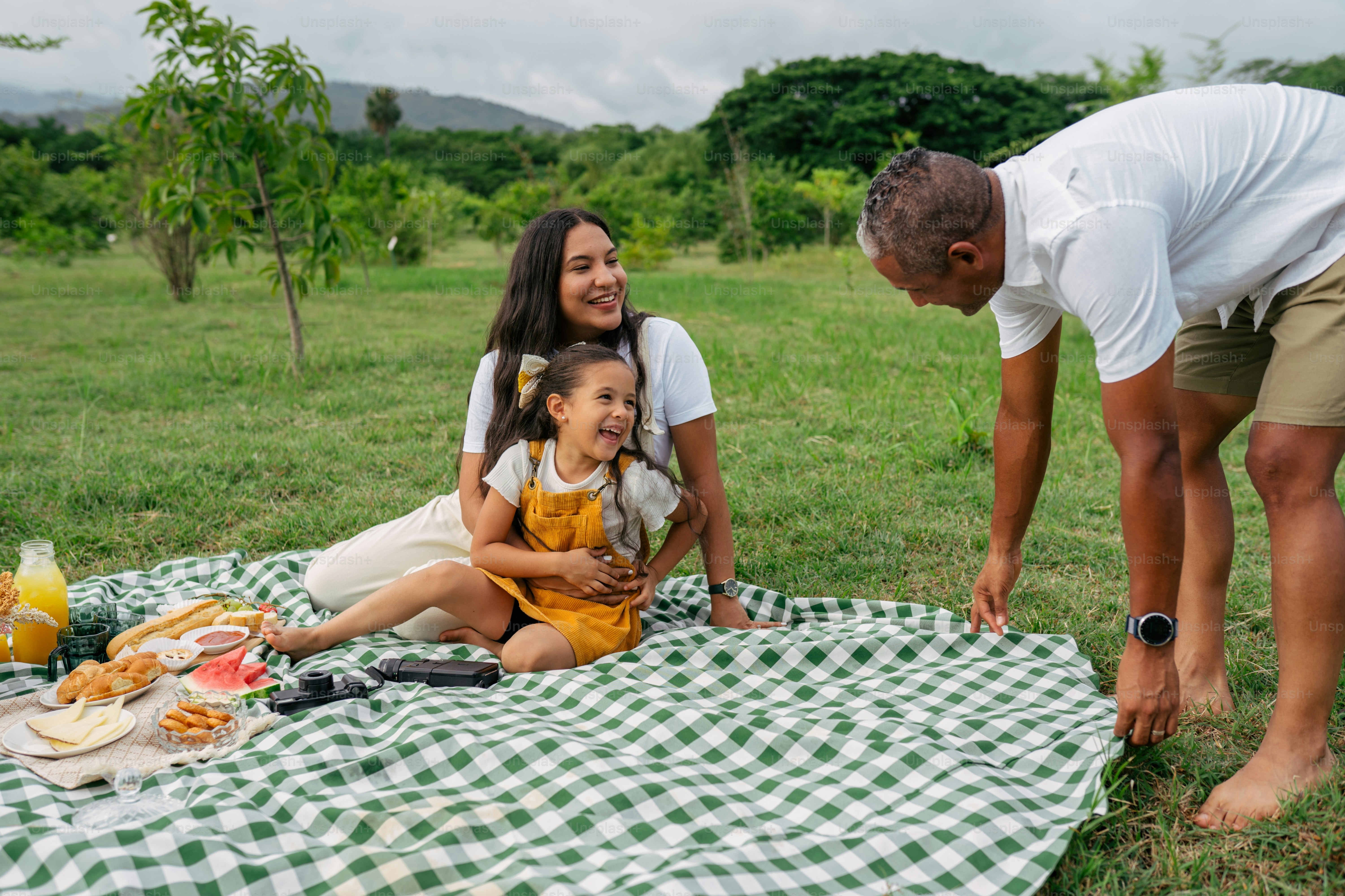 A man and a woman with a child on a picnic blanket