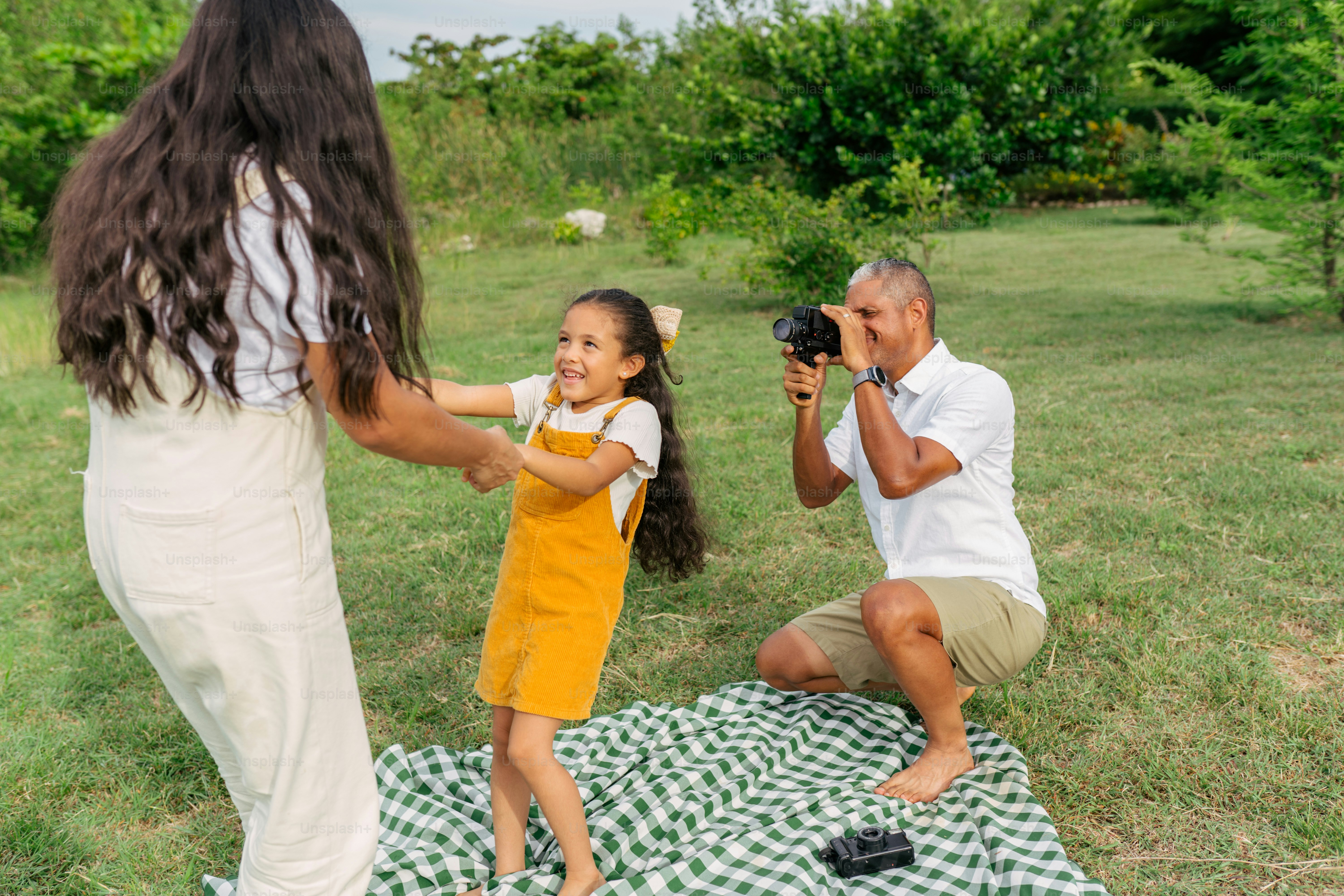 毛布の上で小さな女の子の写真を撮る女性
