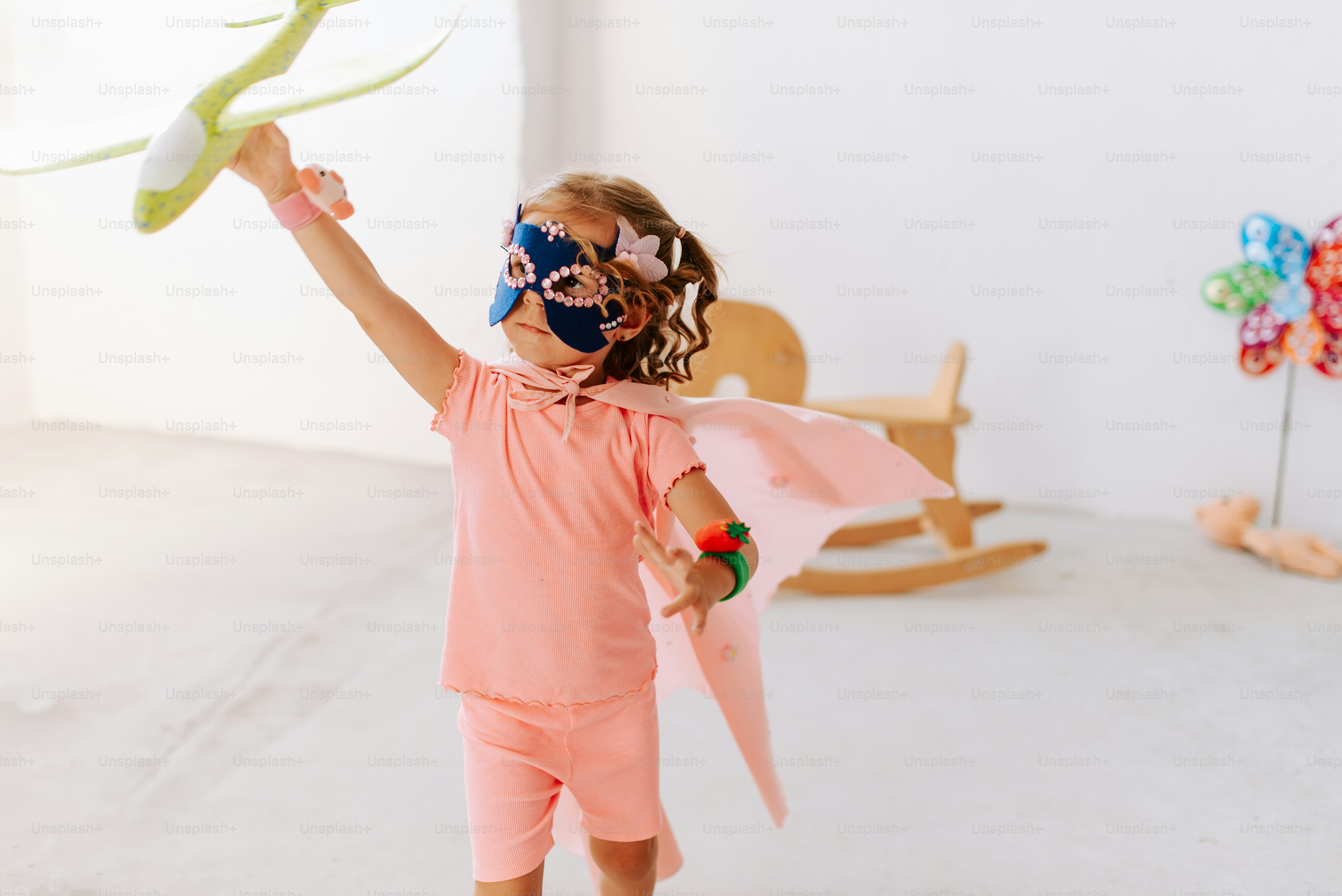 A little girl holding a kite in a room