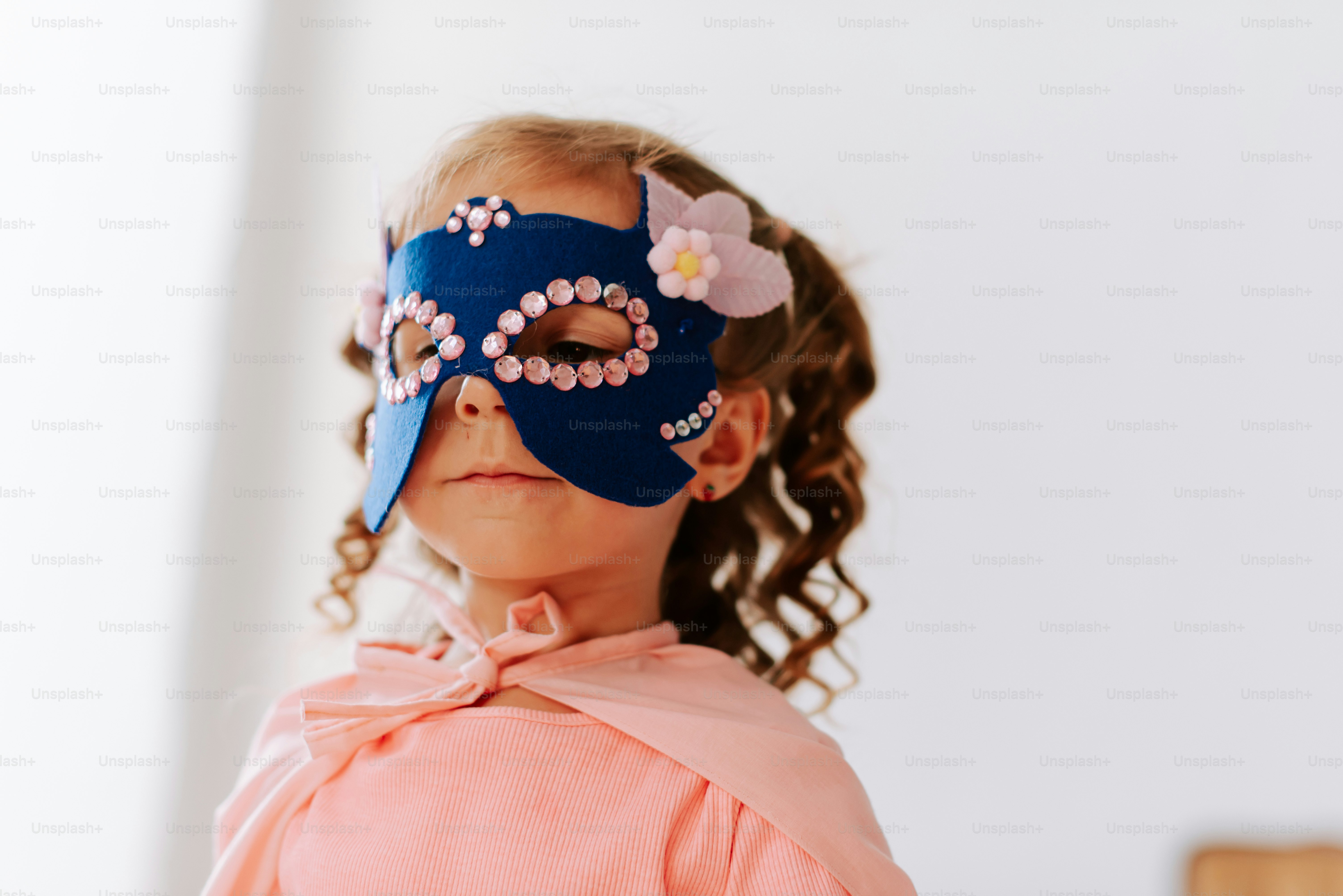 A little girl wearing a blue mask with flowers on it