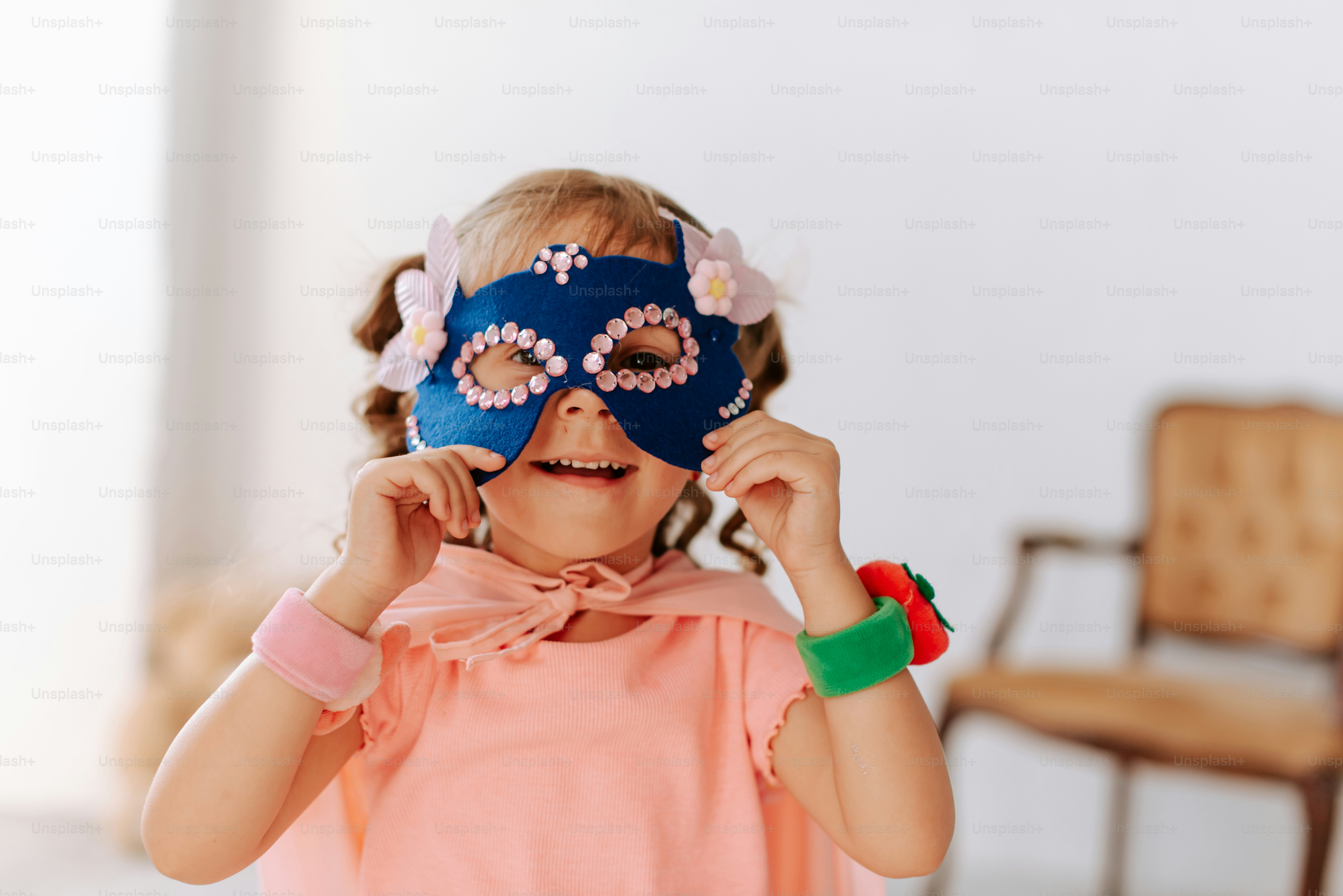 A little girl wearing a blue mask and pink shirt