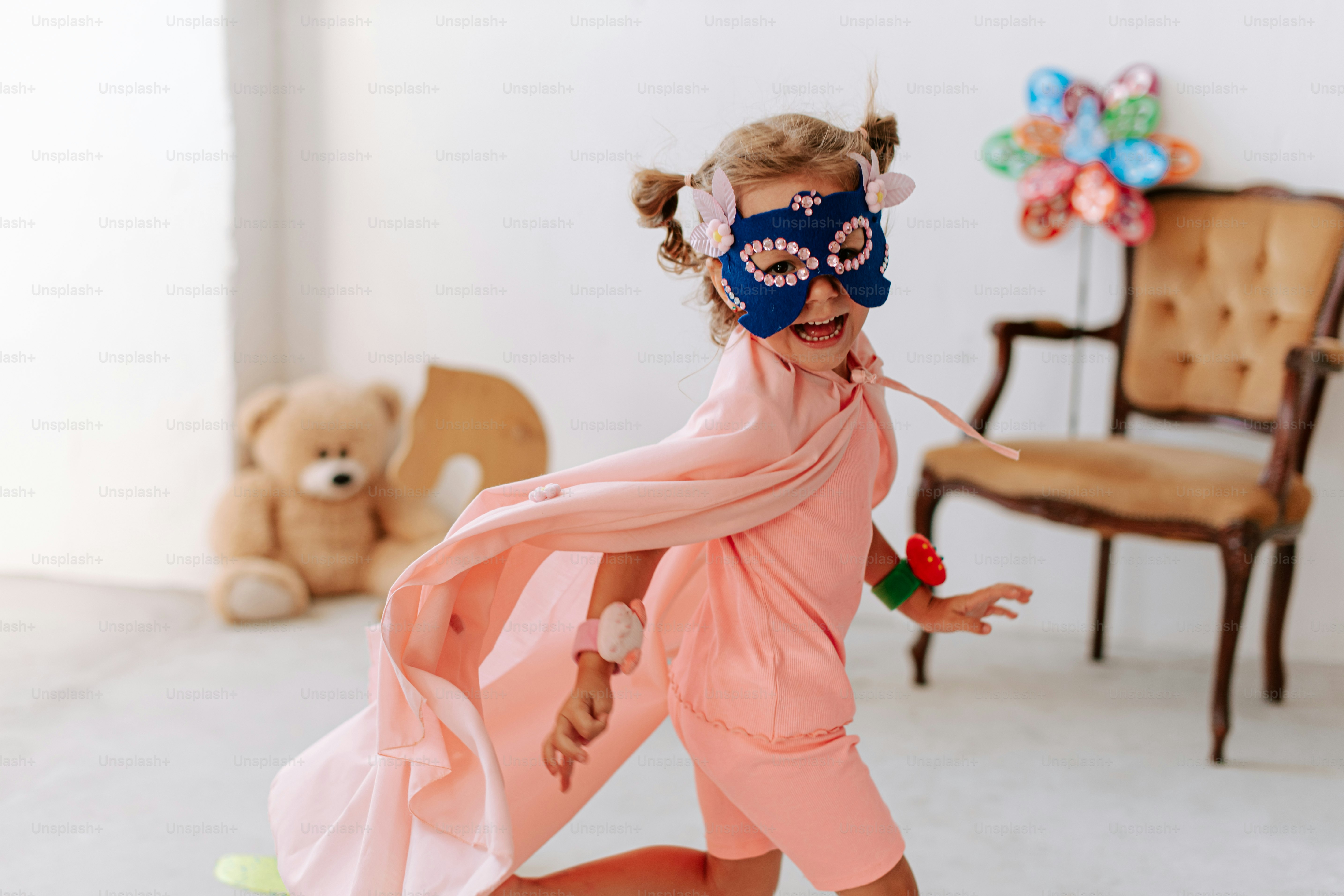 A little girl wearing a mask and a pink dress