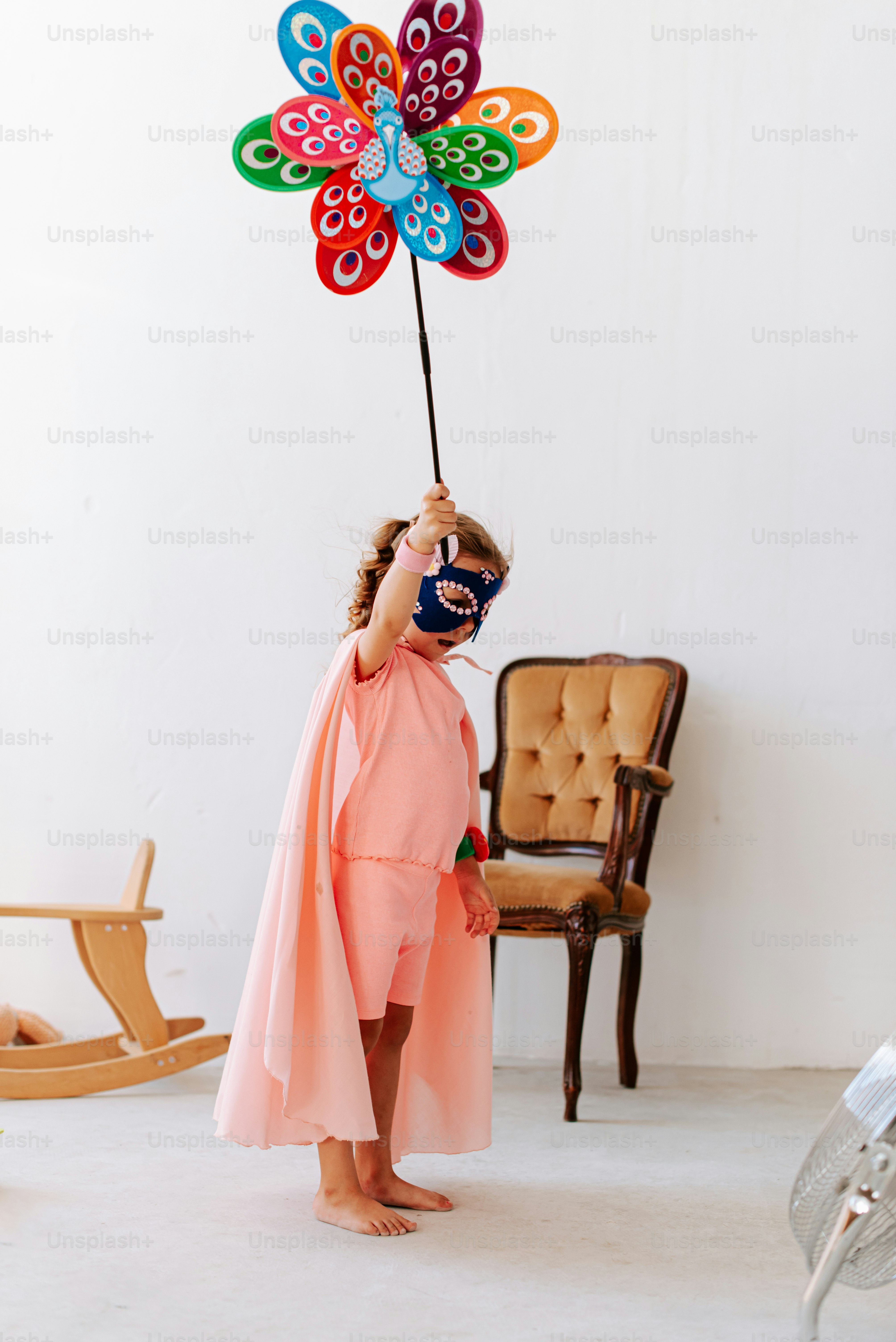 A little girl in a pink dress holding a colorful pinwheel