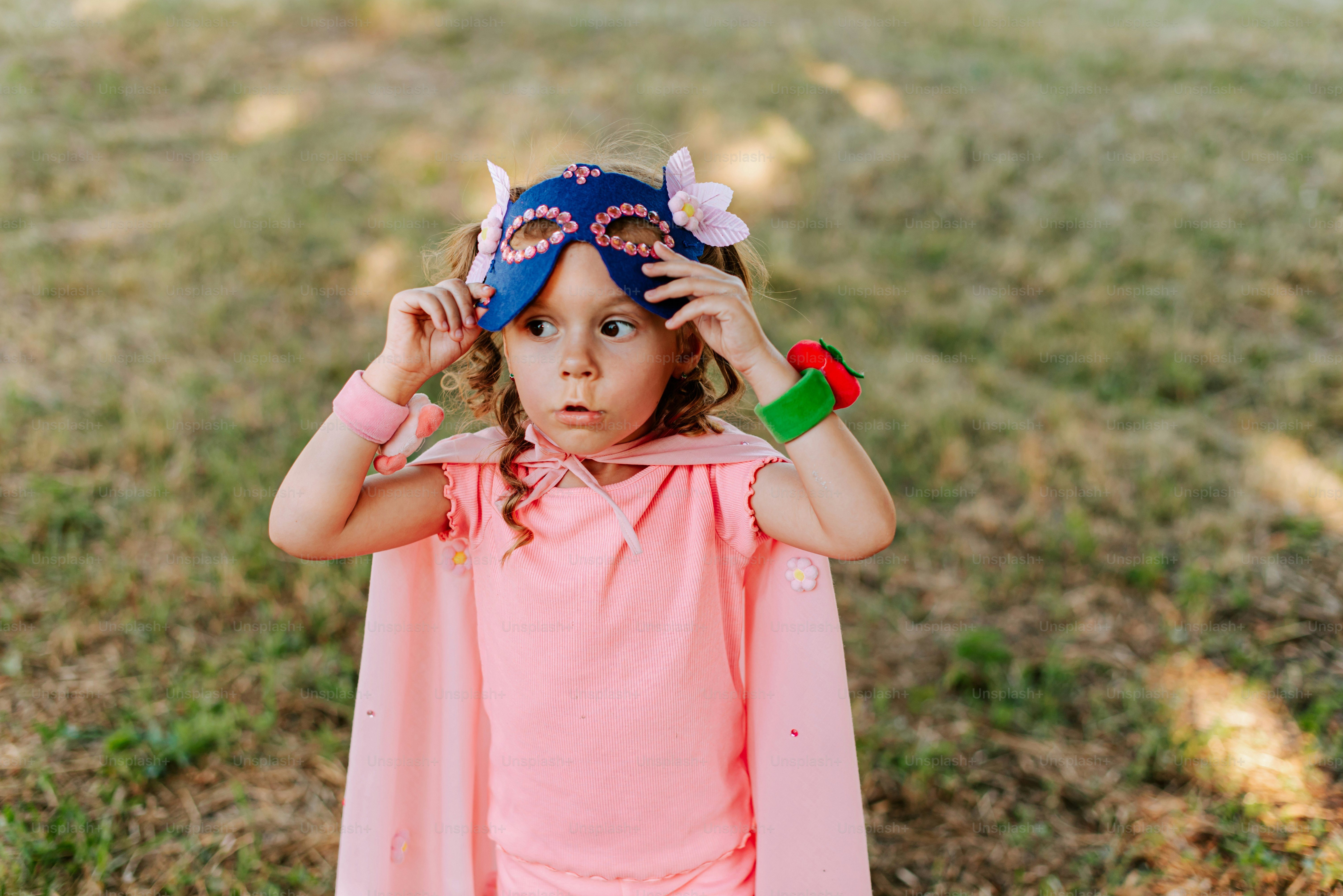 A little girl wearing a pink shirt and a blue mask