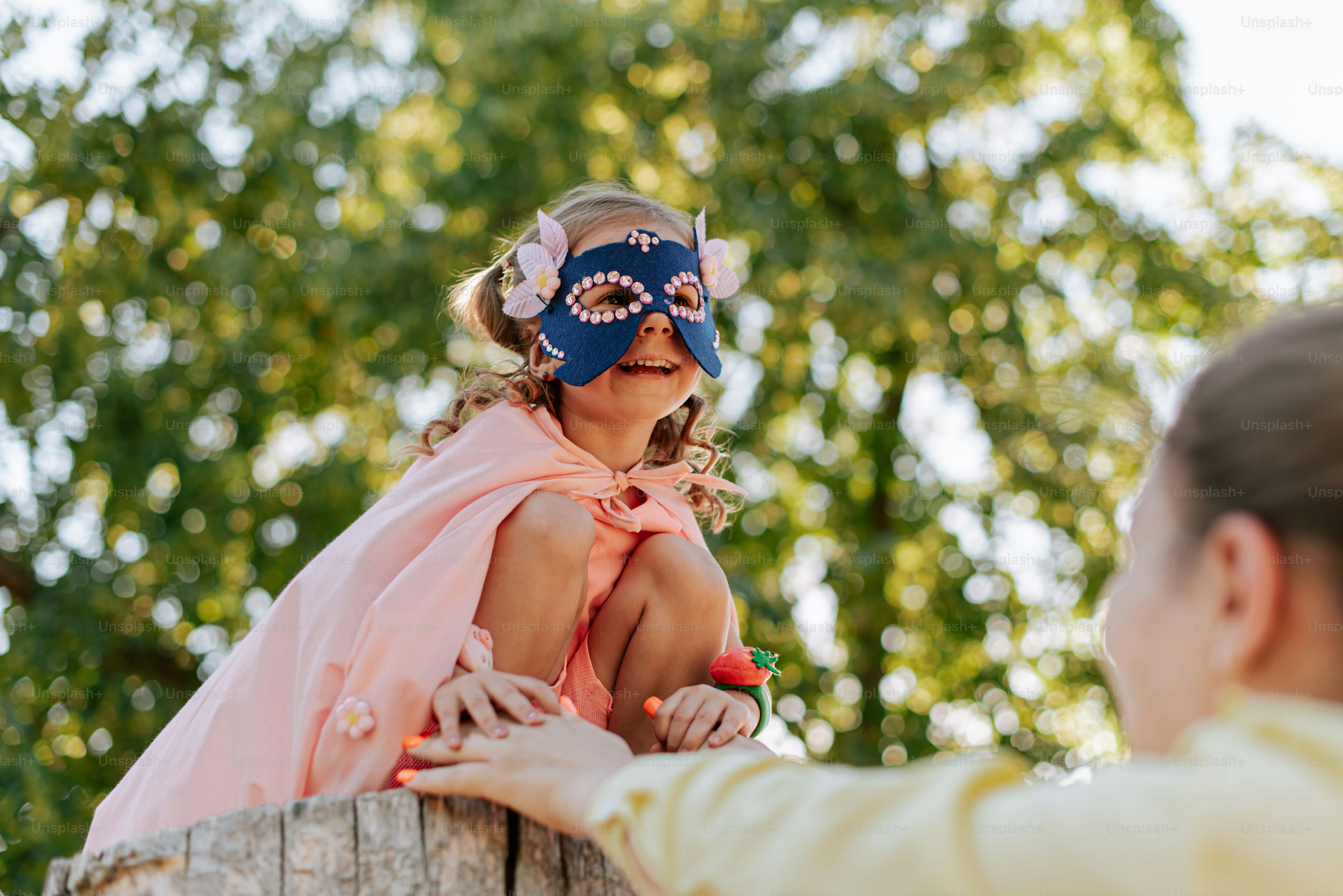 A little girl wearing a mask sitting on a fence