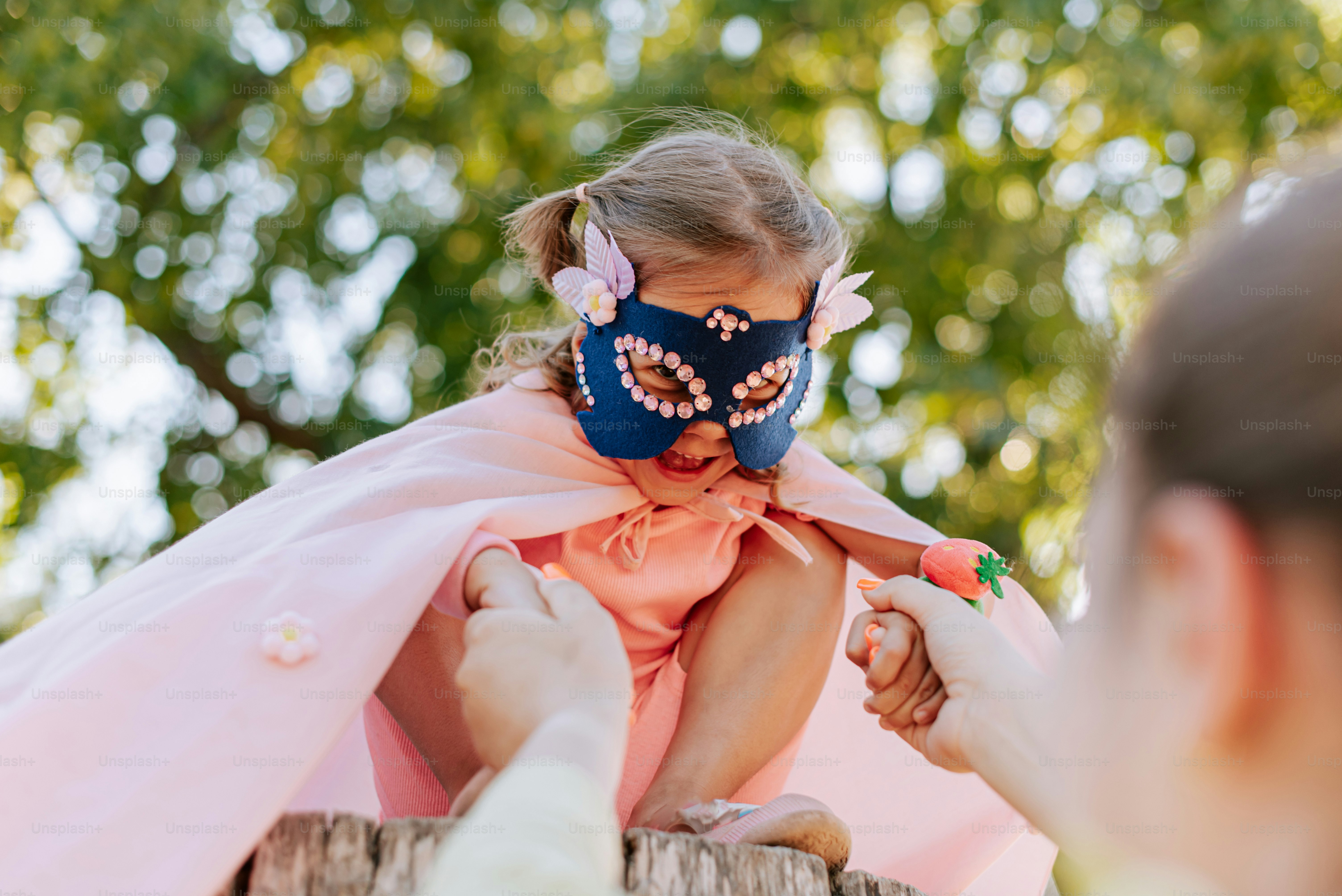 A little girl wearing a mask on top of a wooden fence