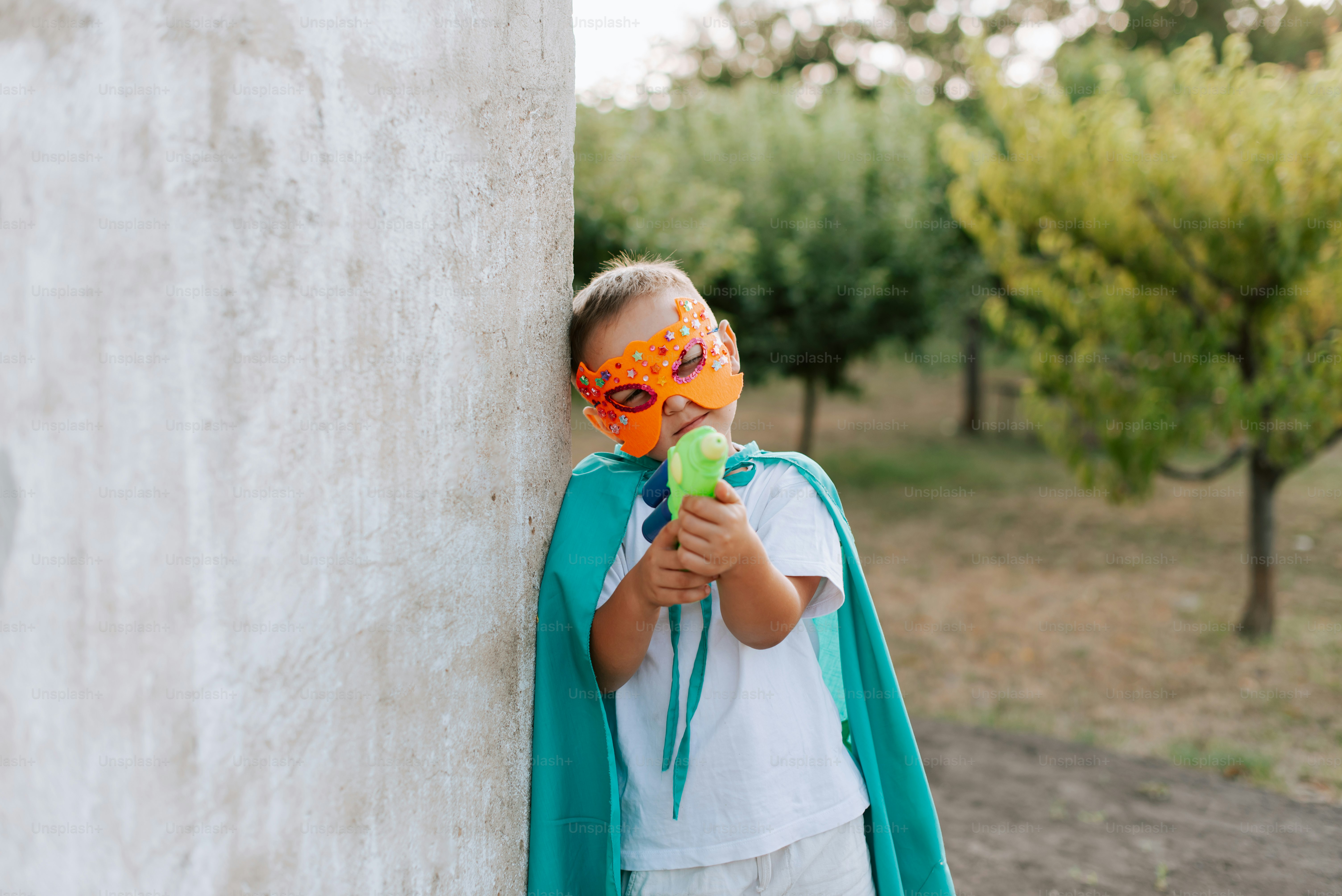 A little girl wearing a green cape and a mask