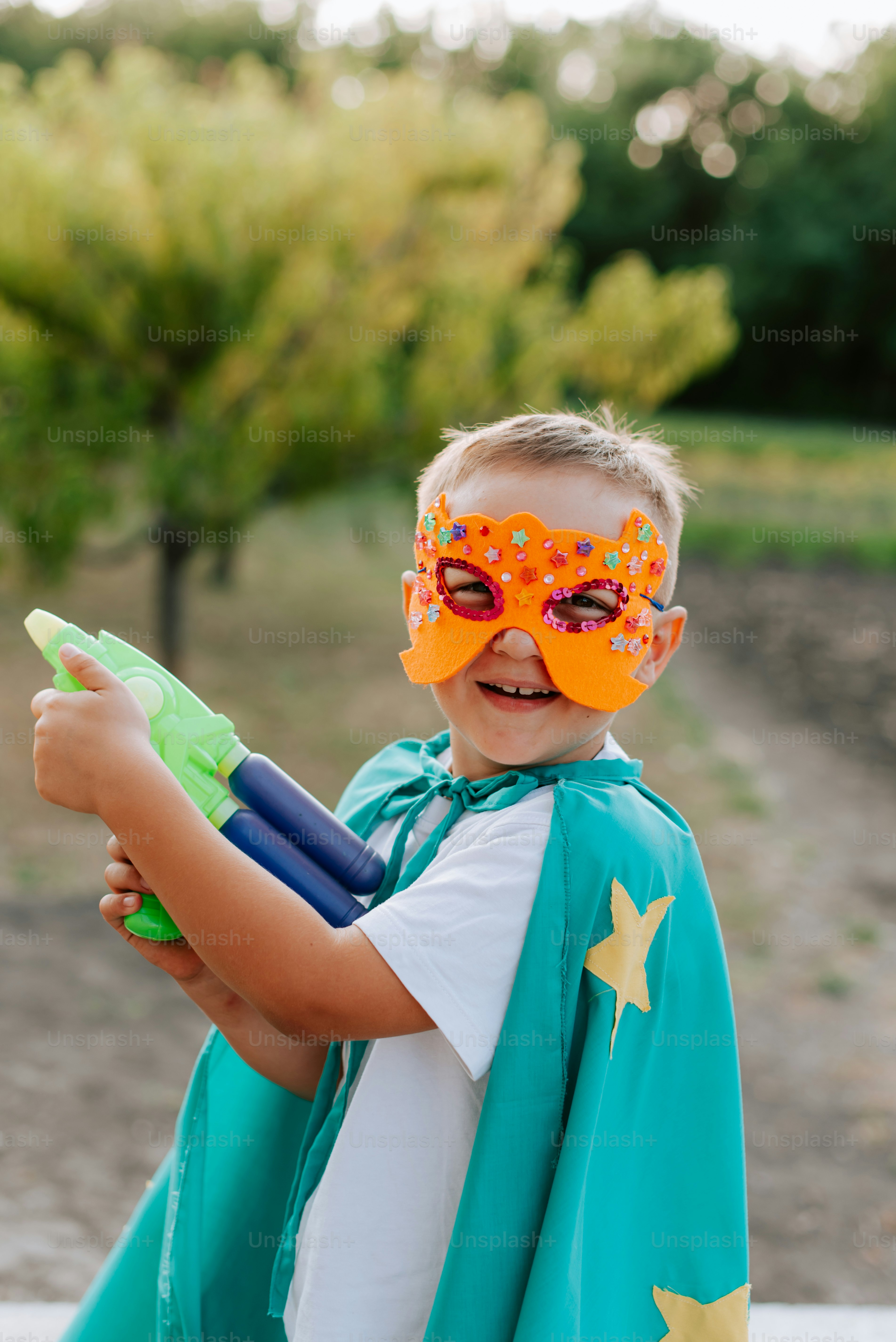 A young boy wearing a green cape and orange mask