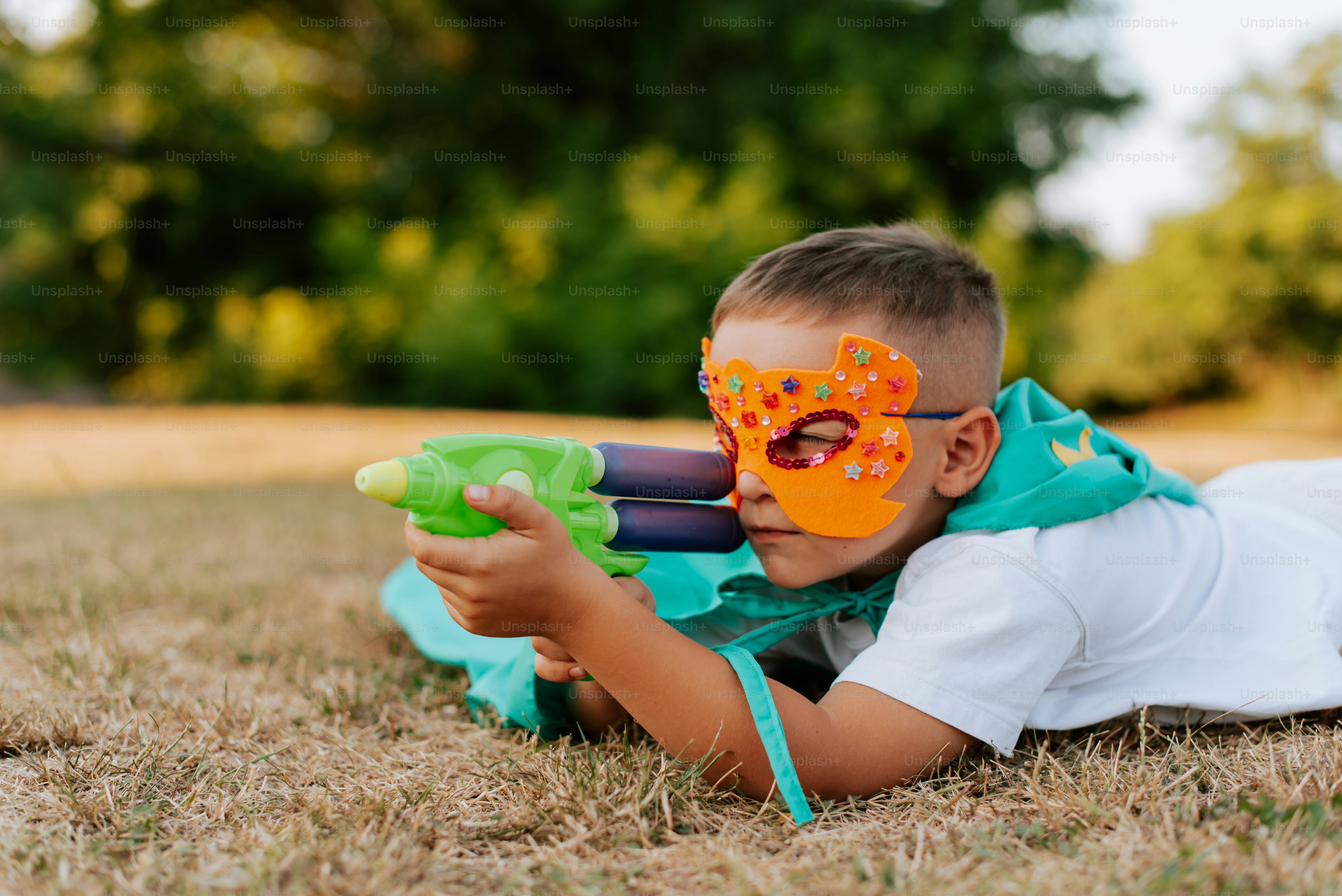 A young boy laying on the ground with a toy gun