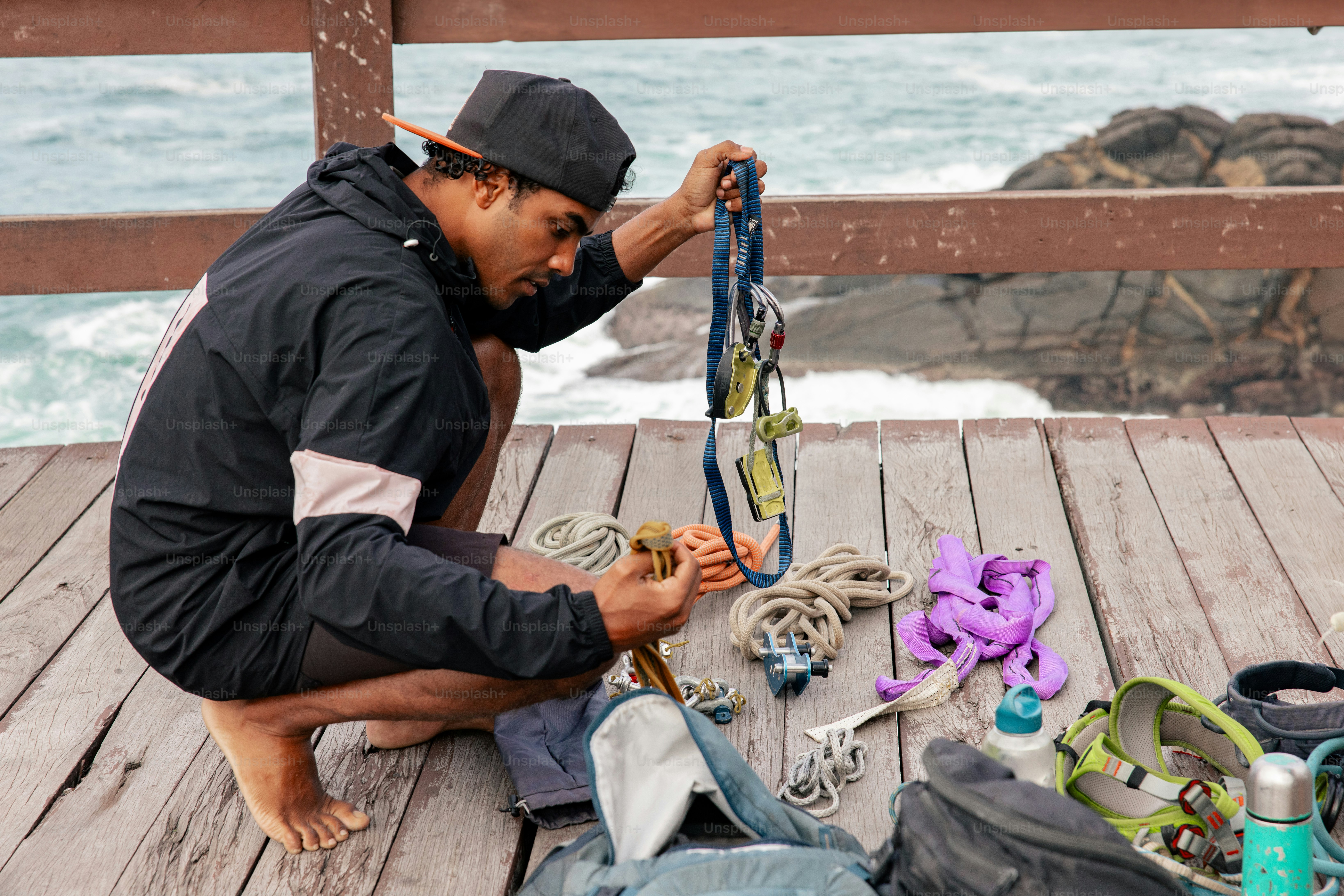 A man sitting on a wooden deck next to a bag