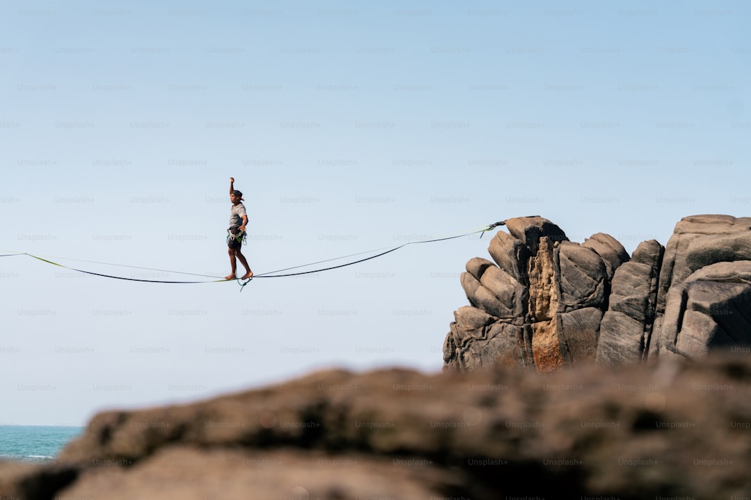 A man walking across a rope over the ocean