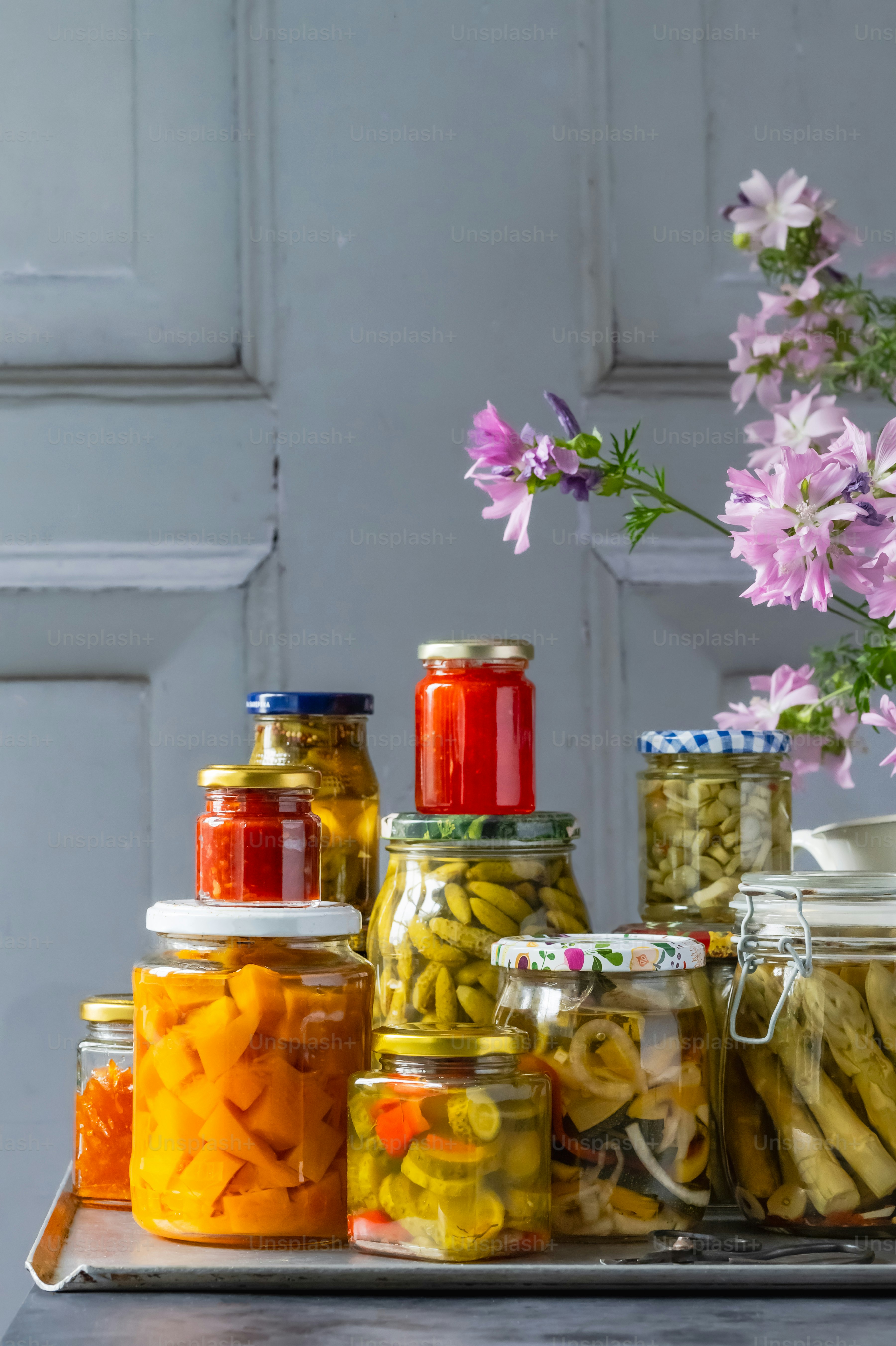 A tray with jars of pickles and flowers